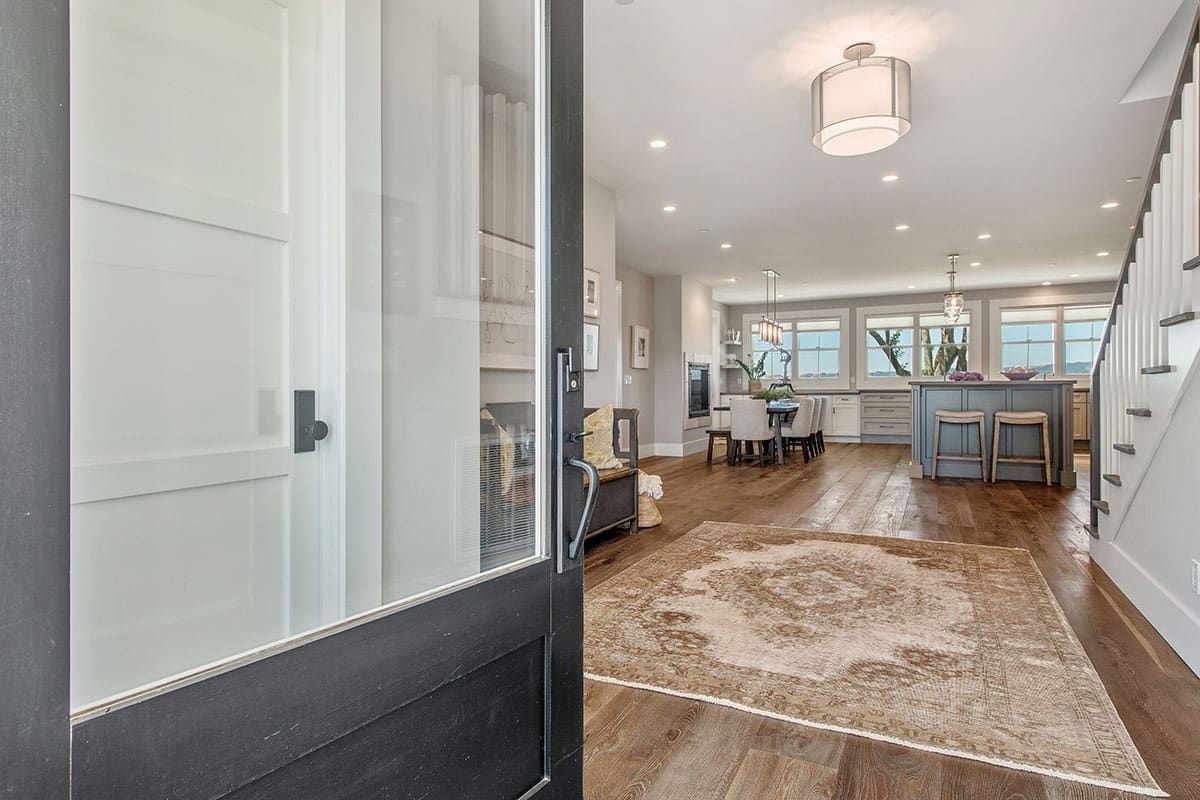 A black door is open to a living room with a rug on the floor.