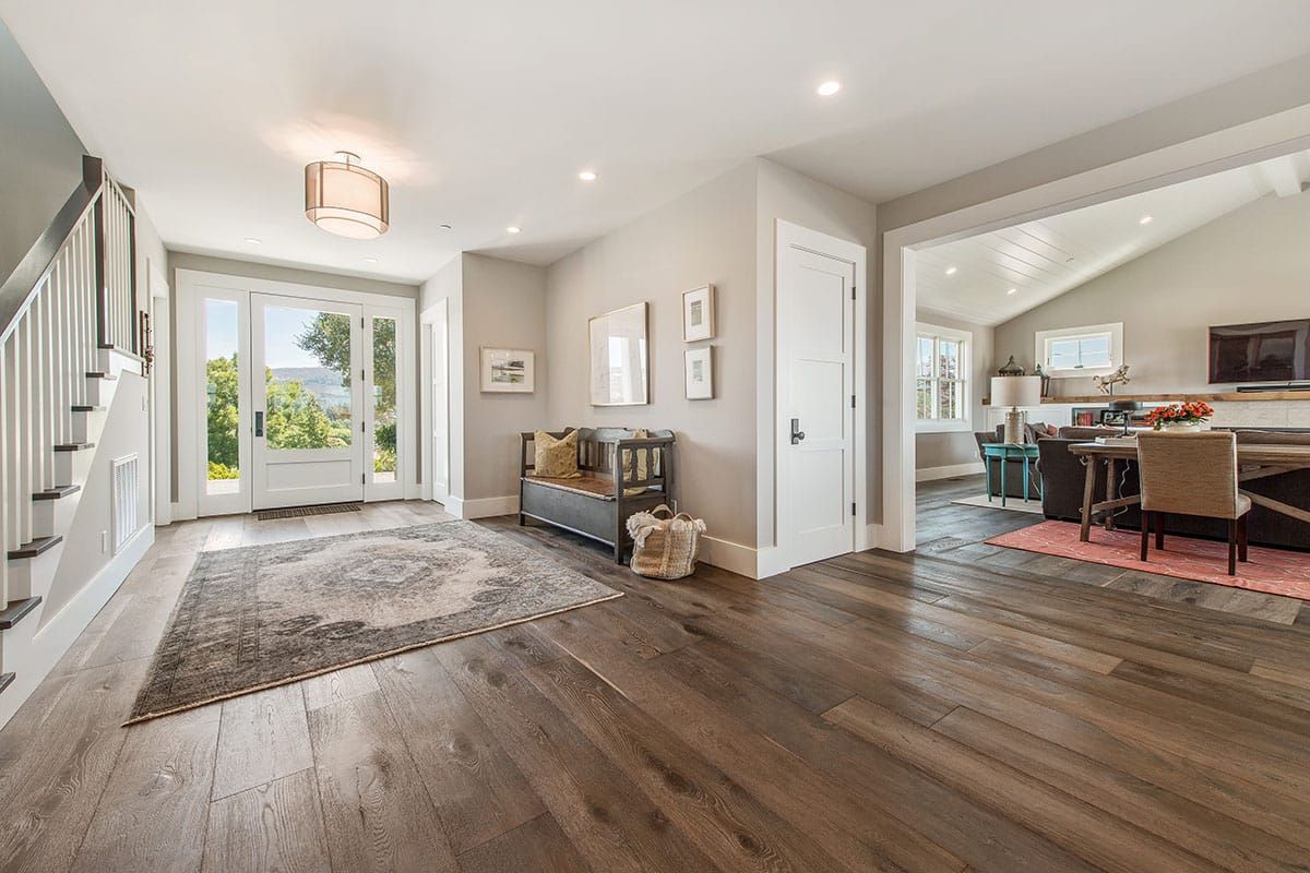 A large hallway in a house with hardwood floors and a bench.