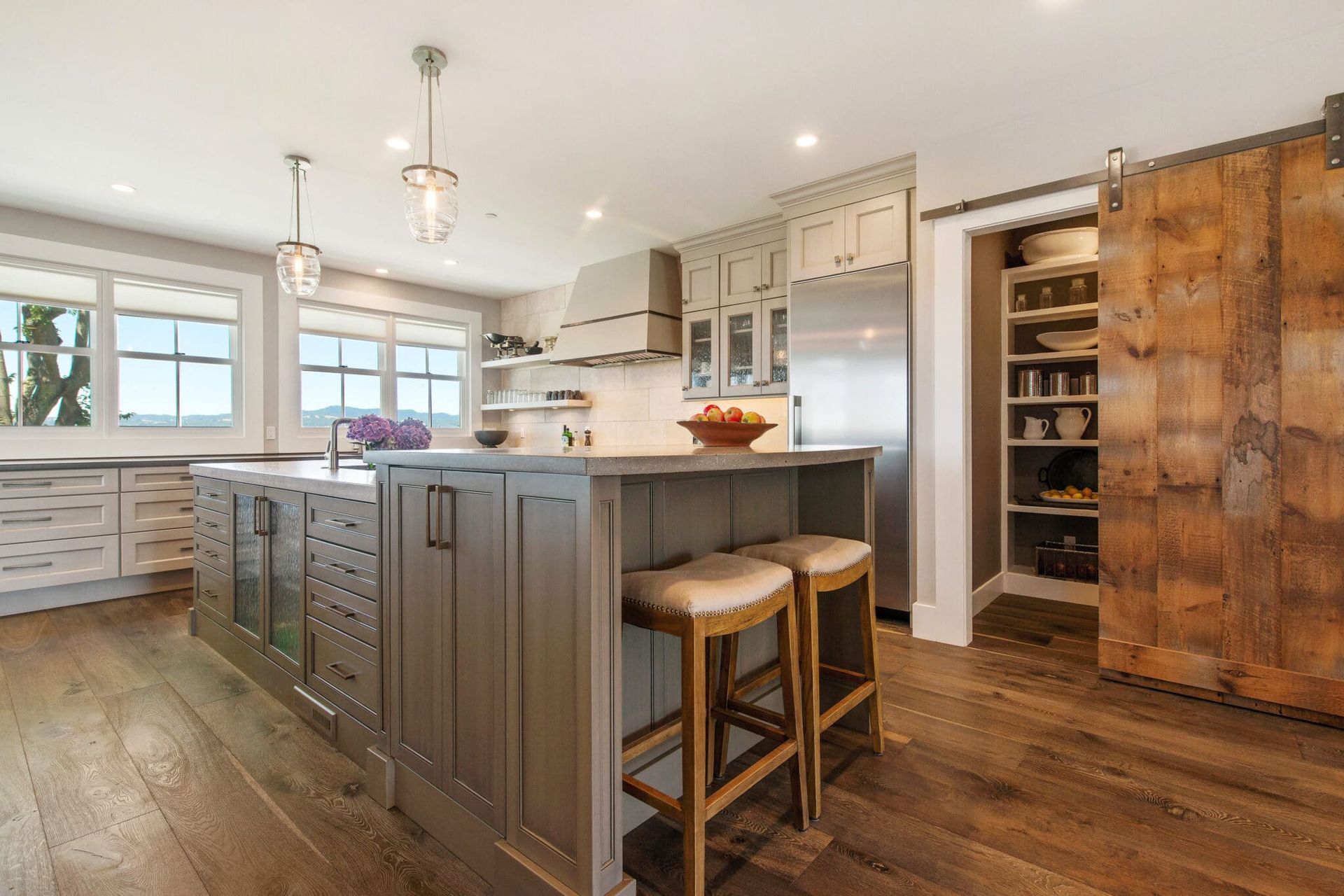 A kitchen with a large island and stools and a sliding barn door.