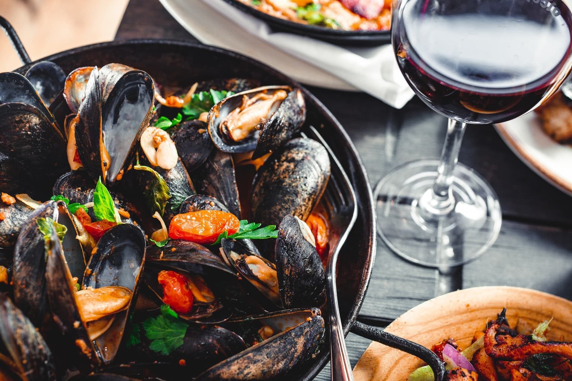 A bowl of mussels and a glass of wine on a table.