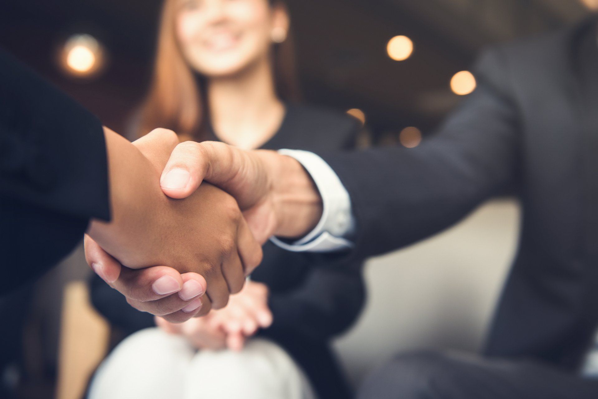 A man and a woman are shaking hands in front of a group of people.