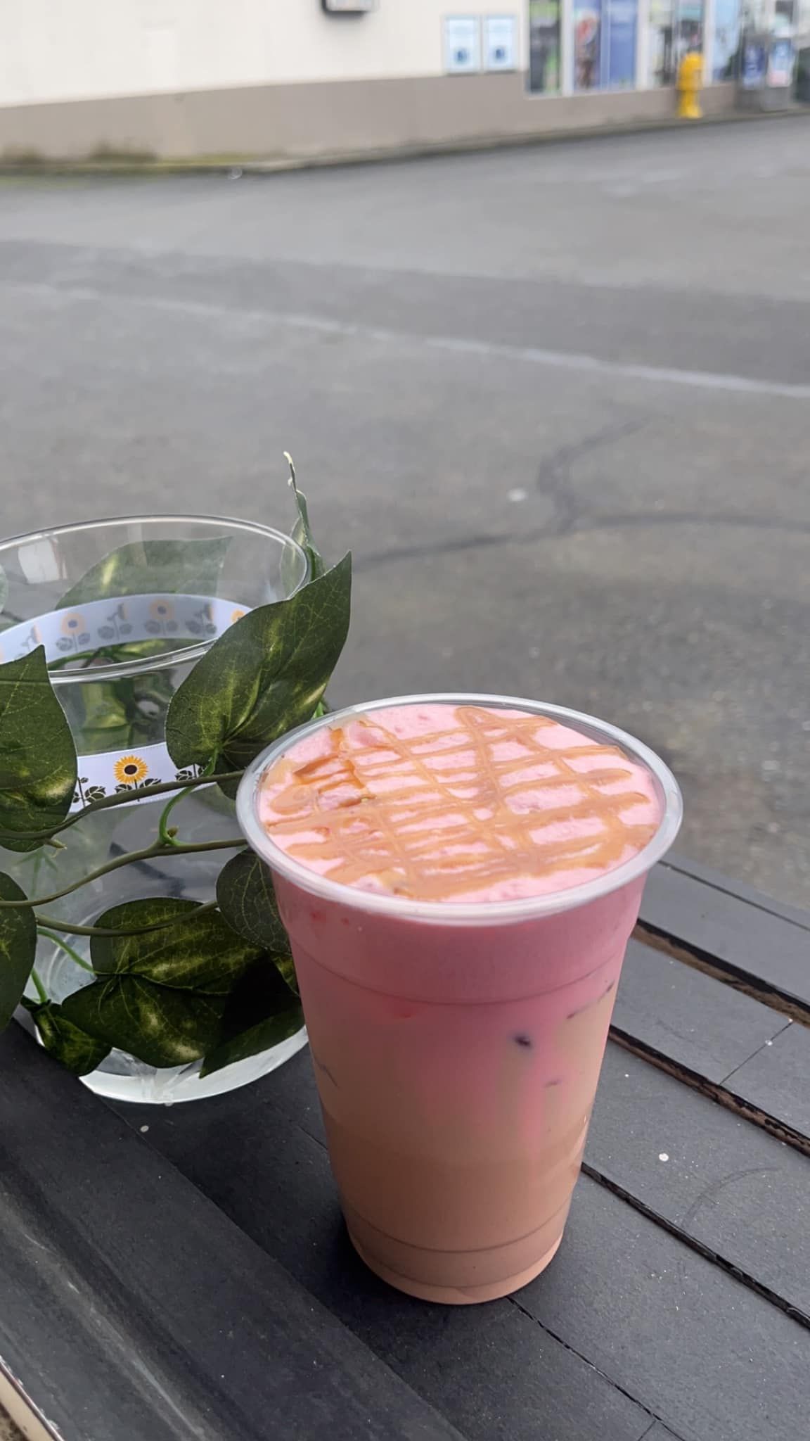A pink drink is sitting on a table next to a vase of flowers.