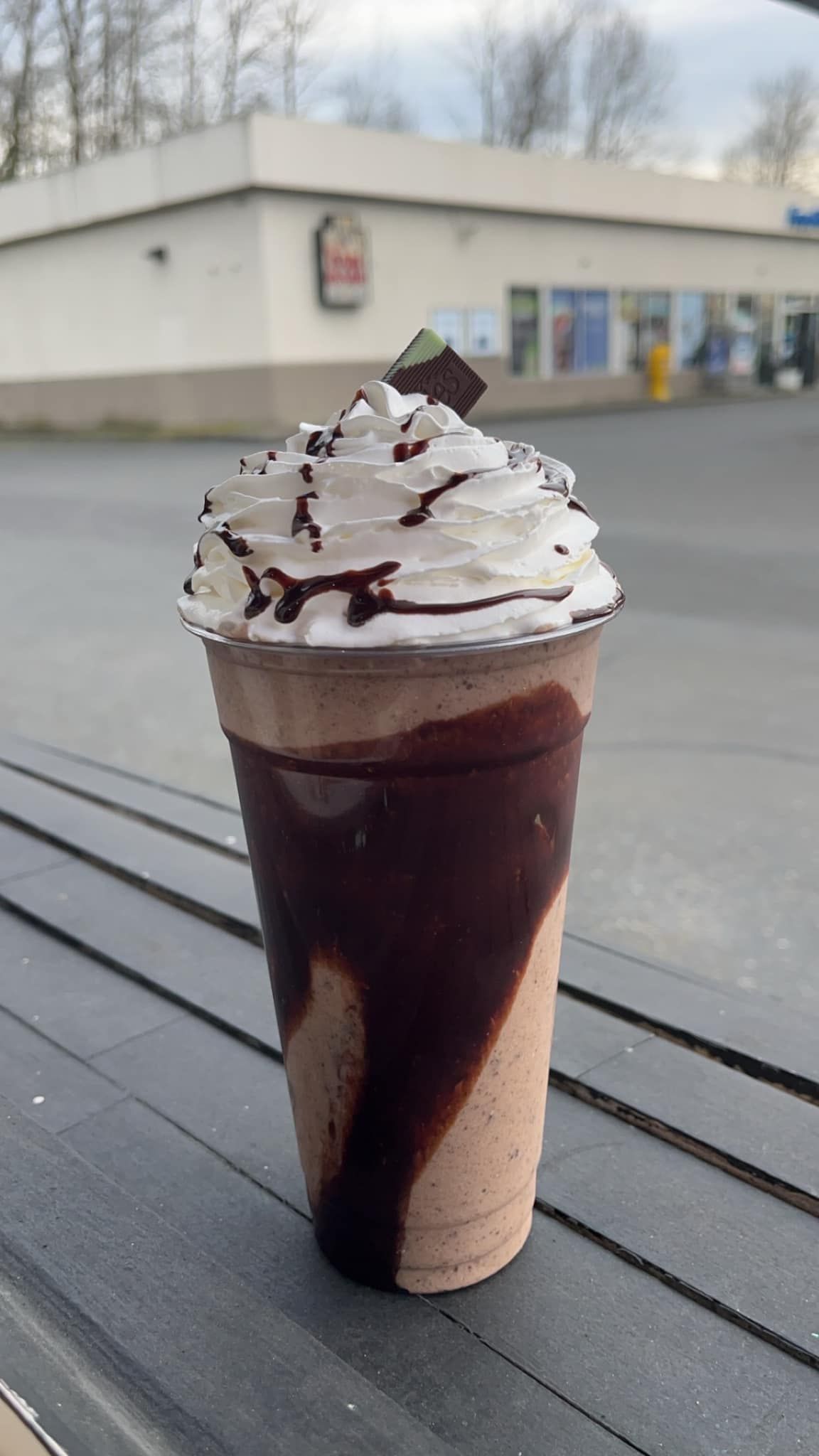 A chocolate milkshake with whipped cream and chocolate sauce is sitting on a table.