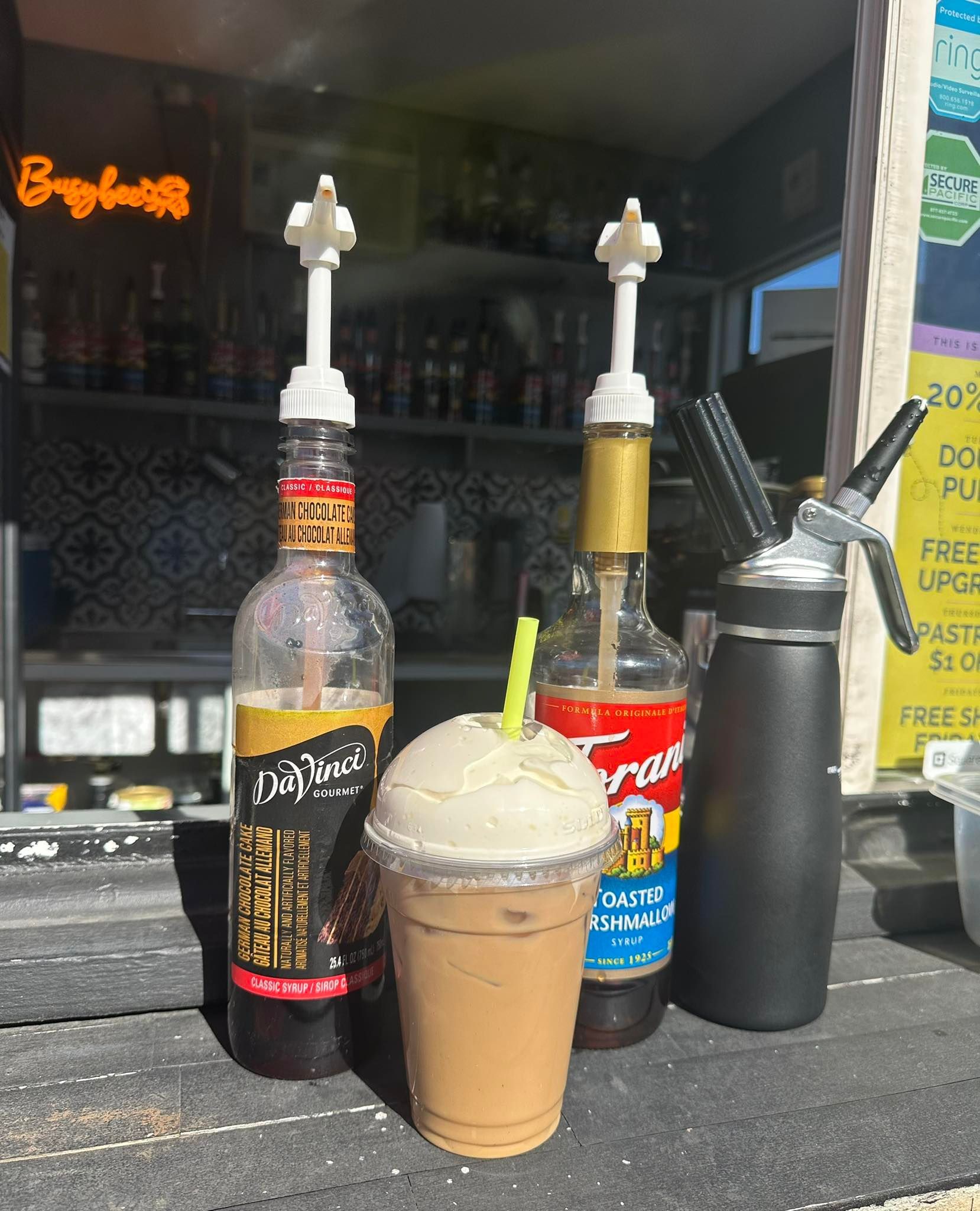 A cup of iced coffee is sitting next to a bottle of soda.