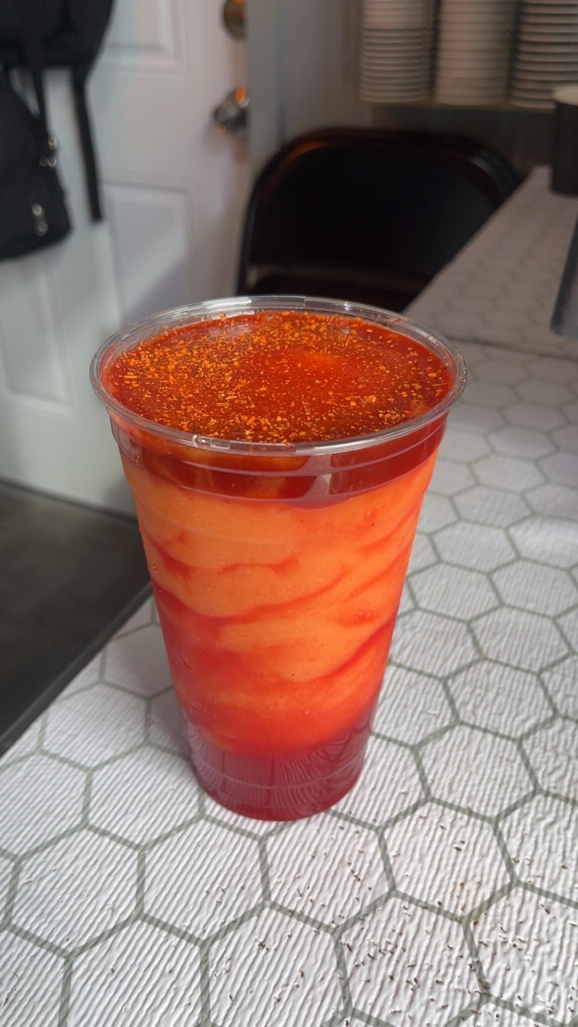 A close up of a drink in a plastic cup on a table.