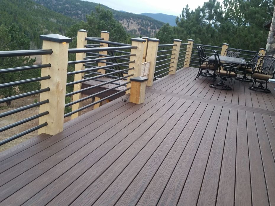 A wooden deck with a metal railing and a table and chairs on it