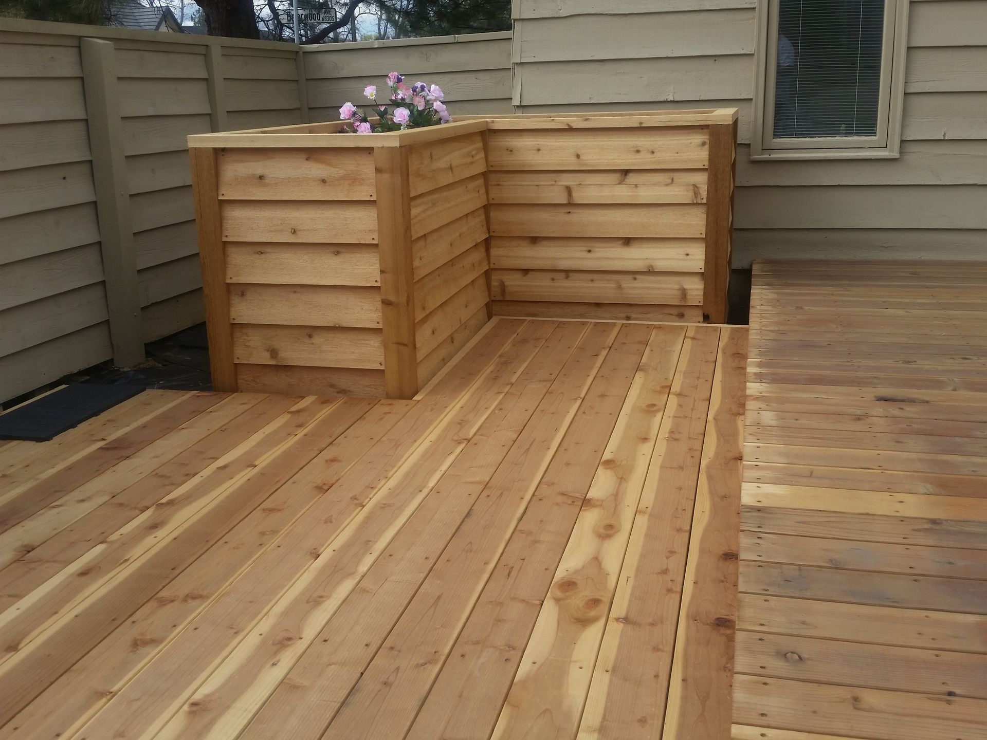 A wooden deck with a planter on top of it