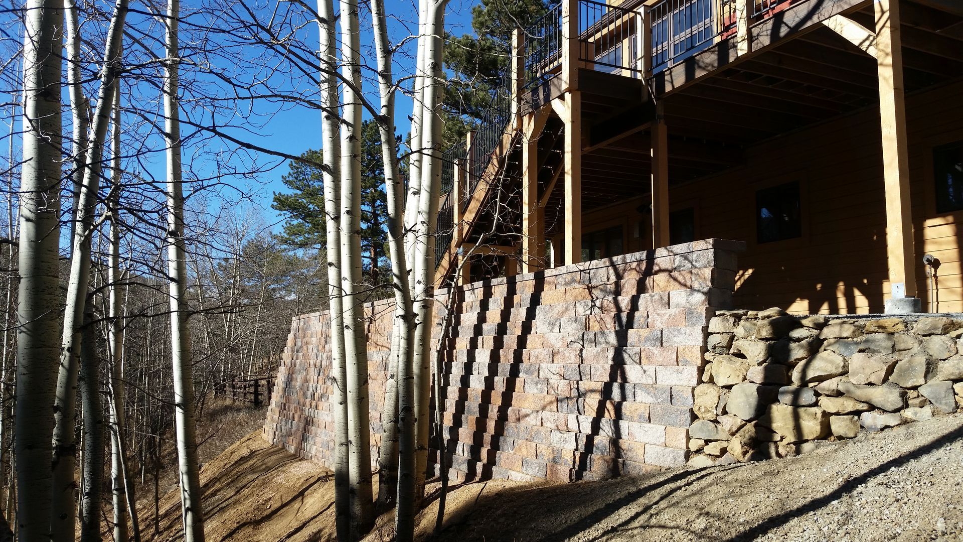 A house is surrounded by trees and a stone wall