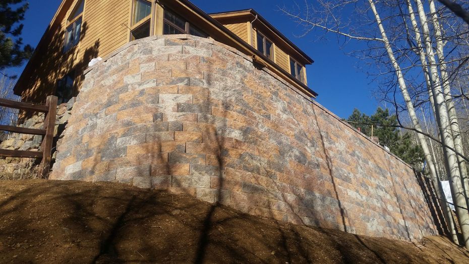 A large rock is in front of a house on a hill