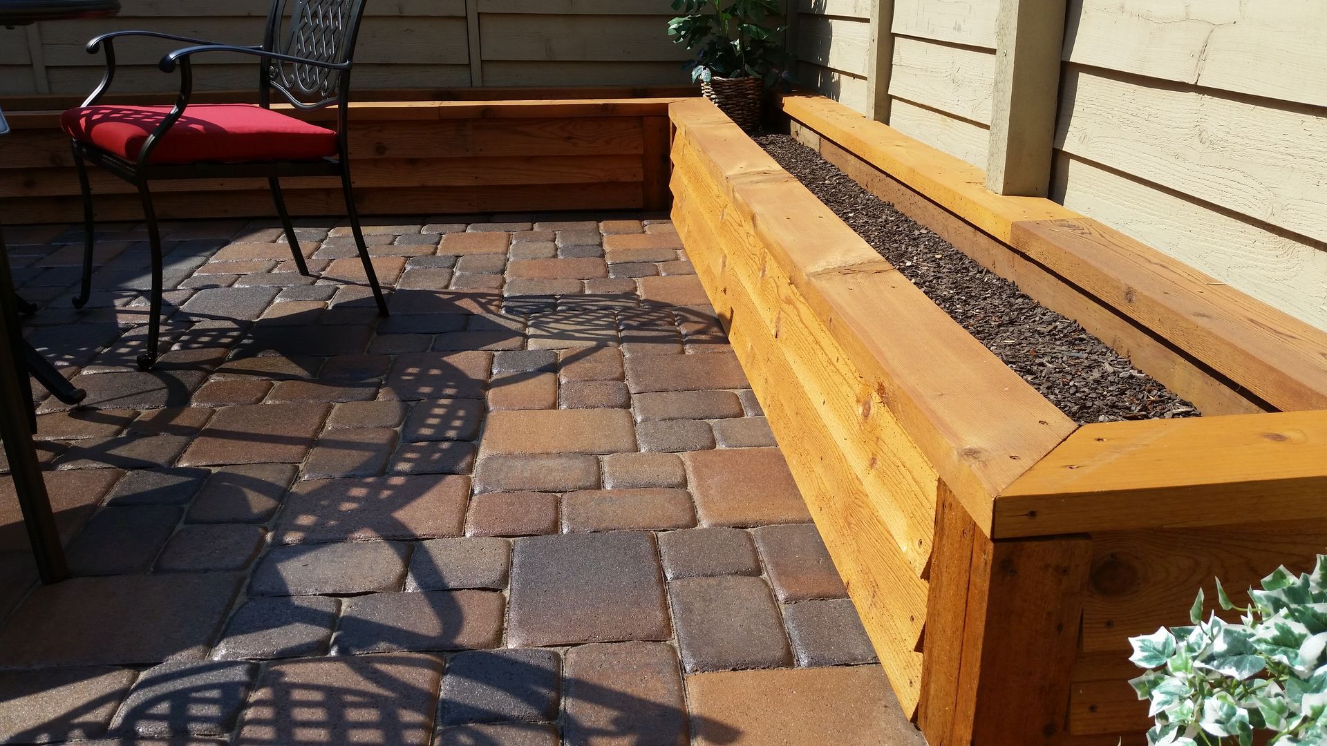 A brick patio with a wooden bench and chairs