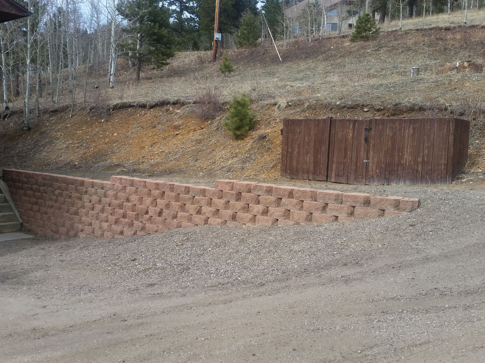 A brick wall is sitting on the side of a dirt road.