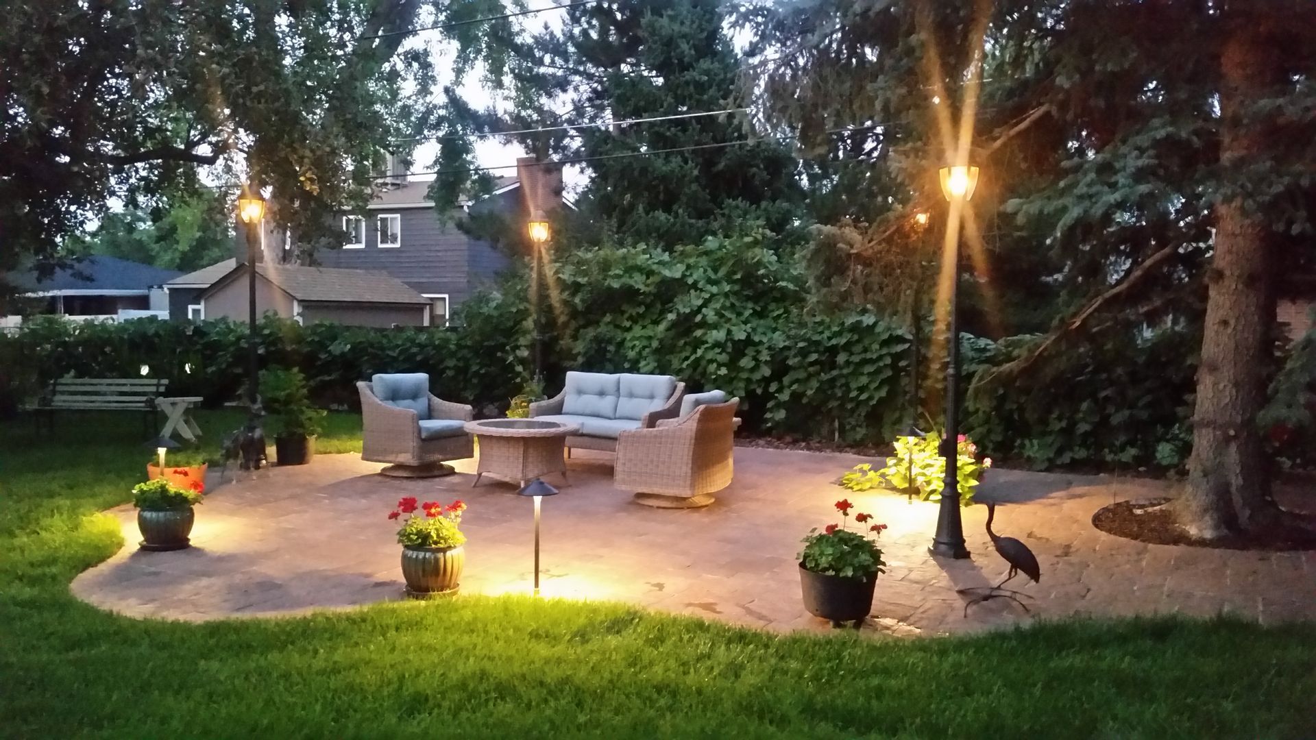 A patio with a fire pit and chairs is lit up at night
