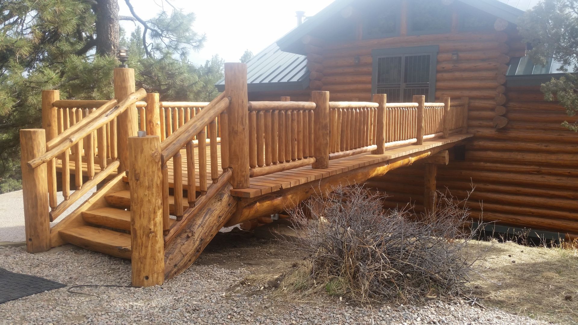 A log cabin with a wooden deck and stairs leading up to it.