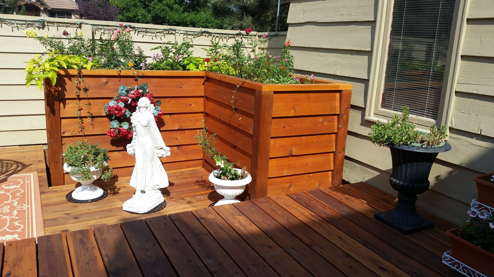 A wooden deck with planters and a statue on it