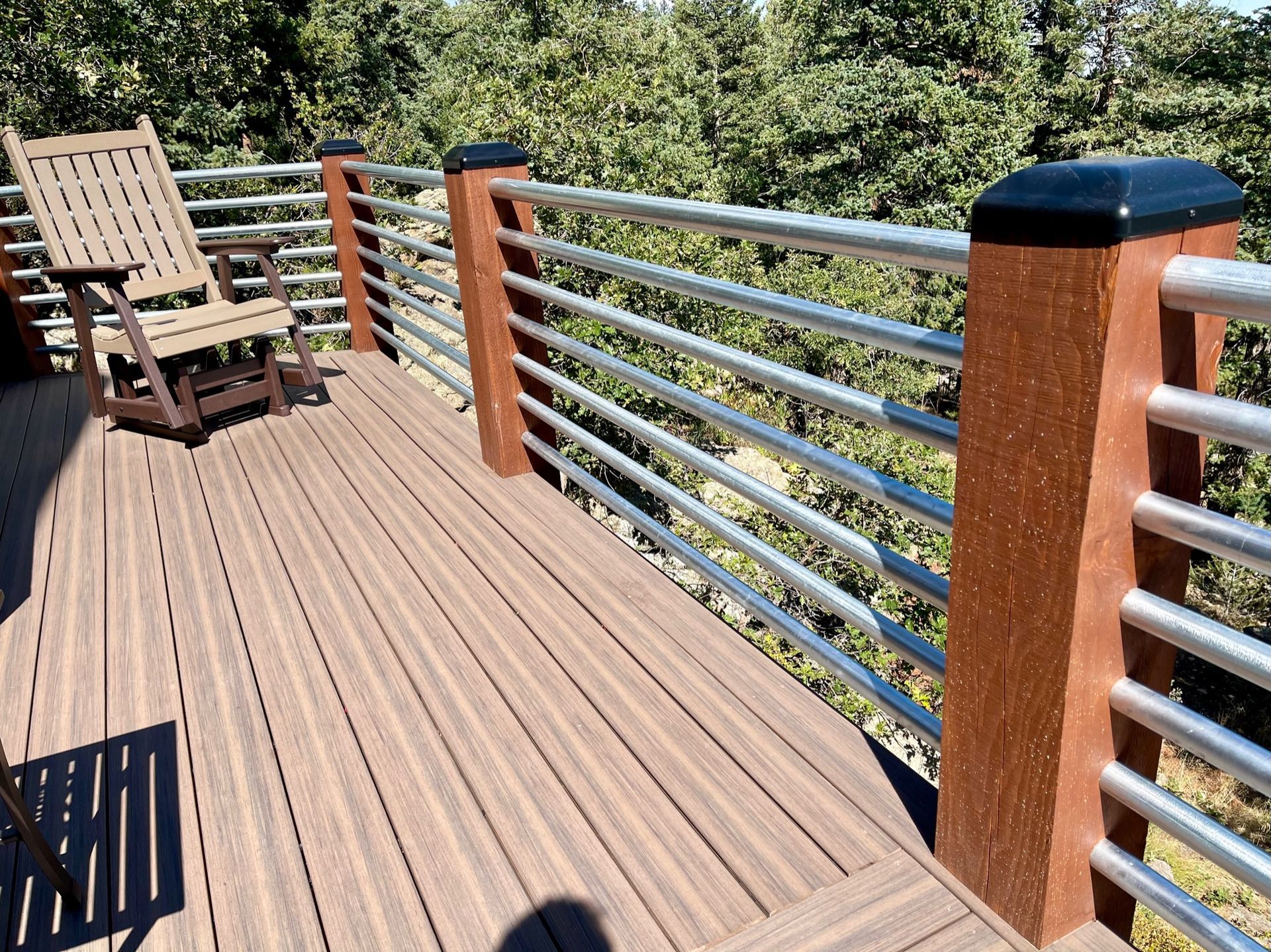 A wooden deck with a metal railing and a chair on it.