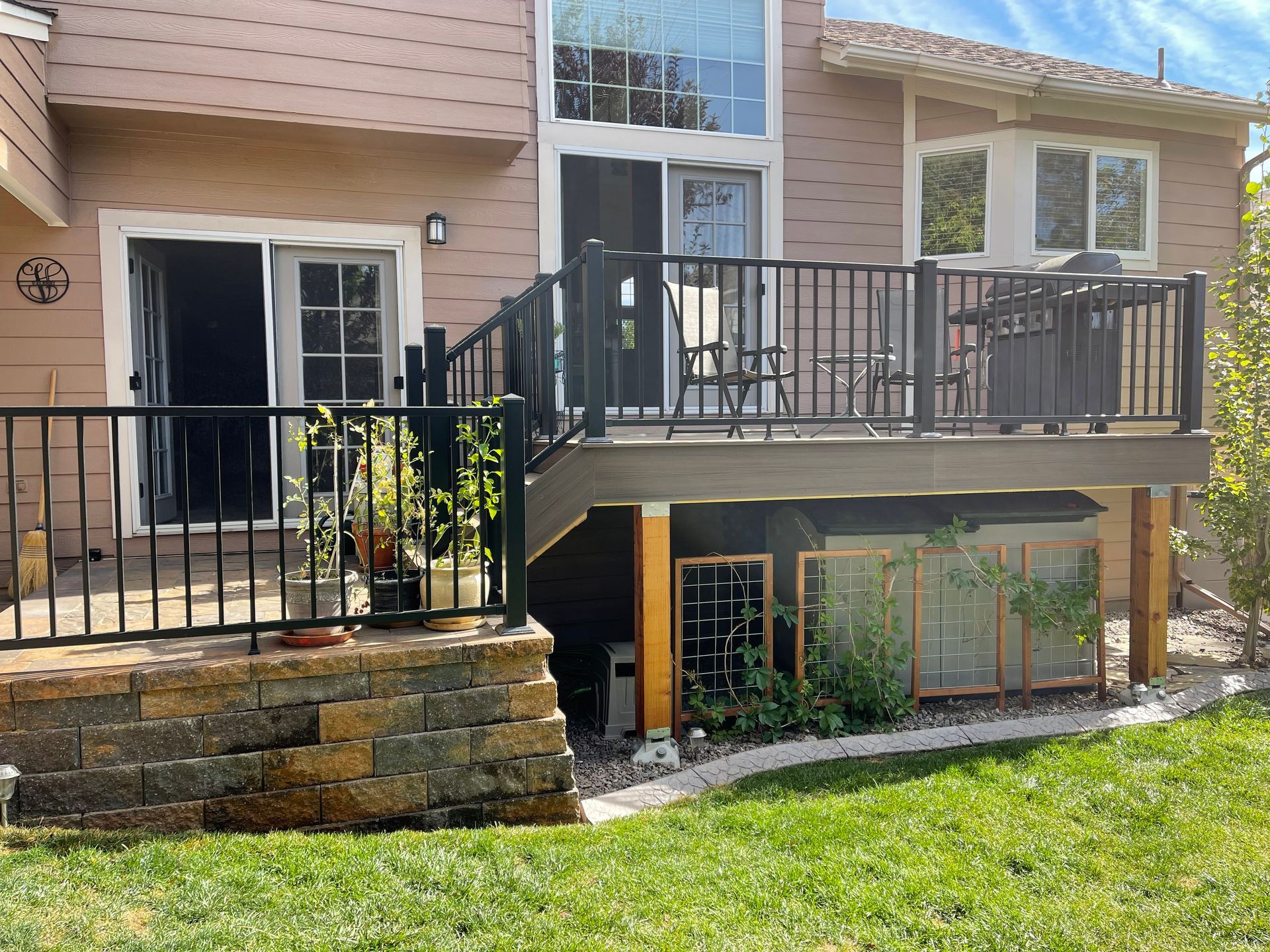 The back of a house with a large deck and stairs leading up to it.