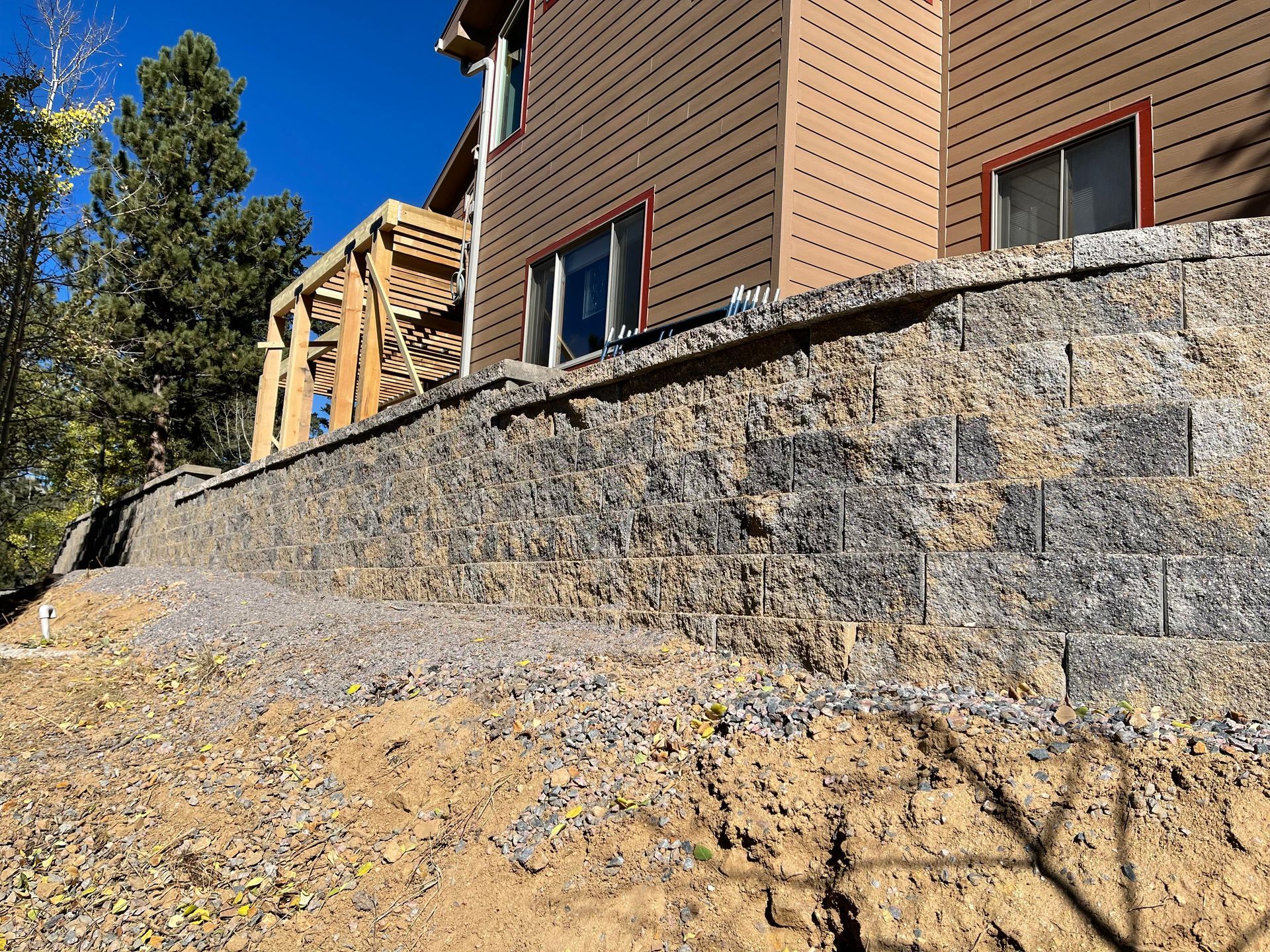 There is a large stone wall in front of a house.