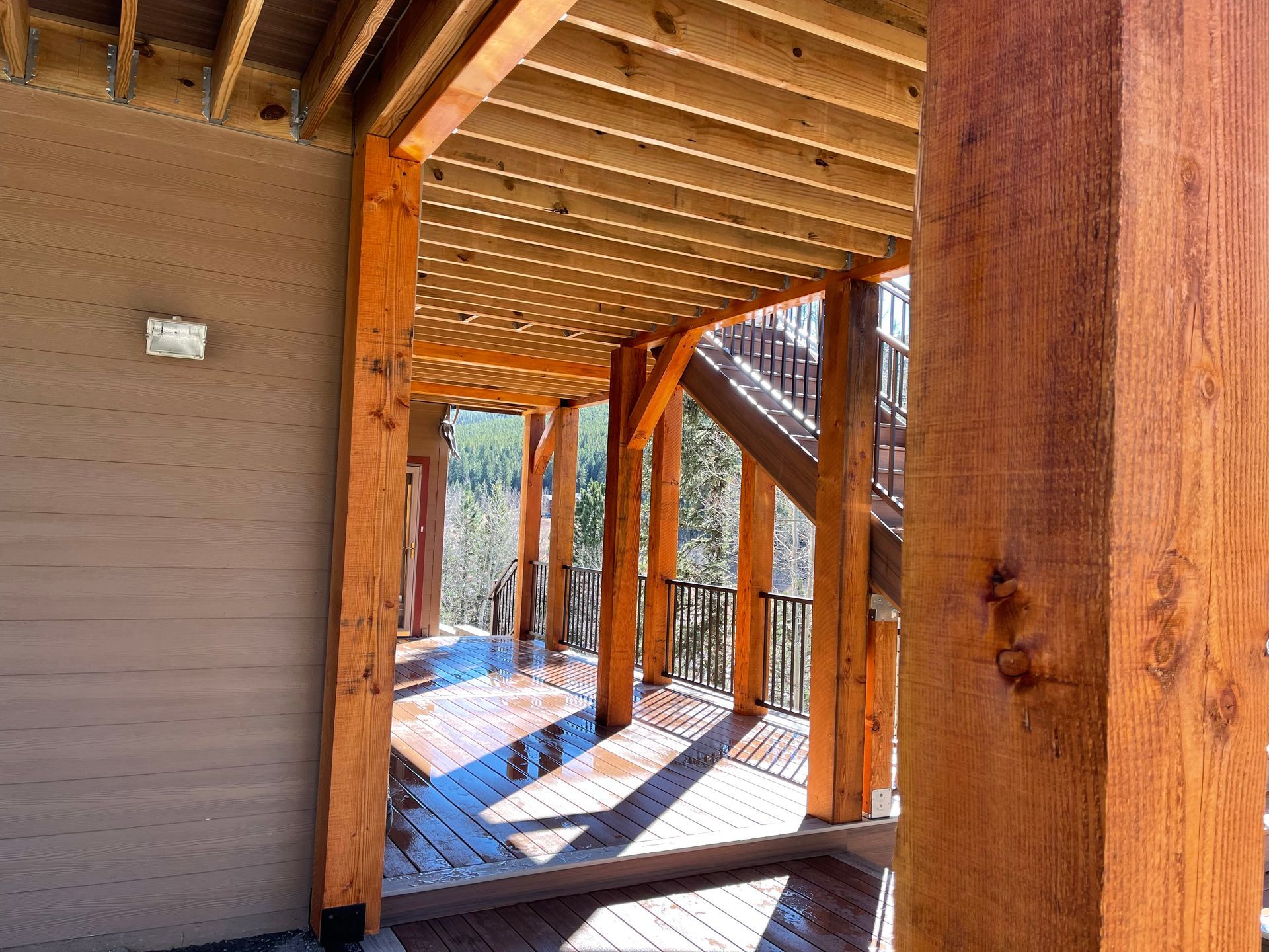 A wooden deck with a pergola and stairs underneath it.