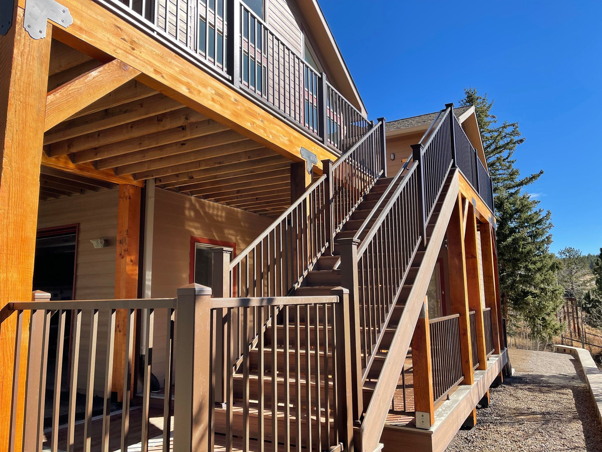 A wooden deck with stairs leading up to the second floor of a house.