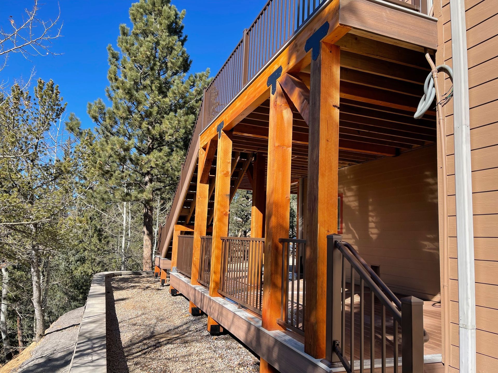 A wooden deck with stairs leading up to it is surrounded by trees.