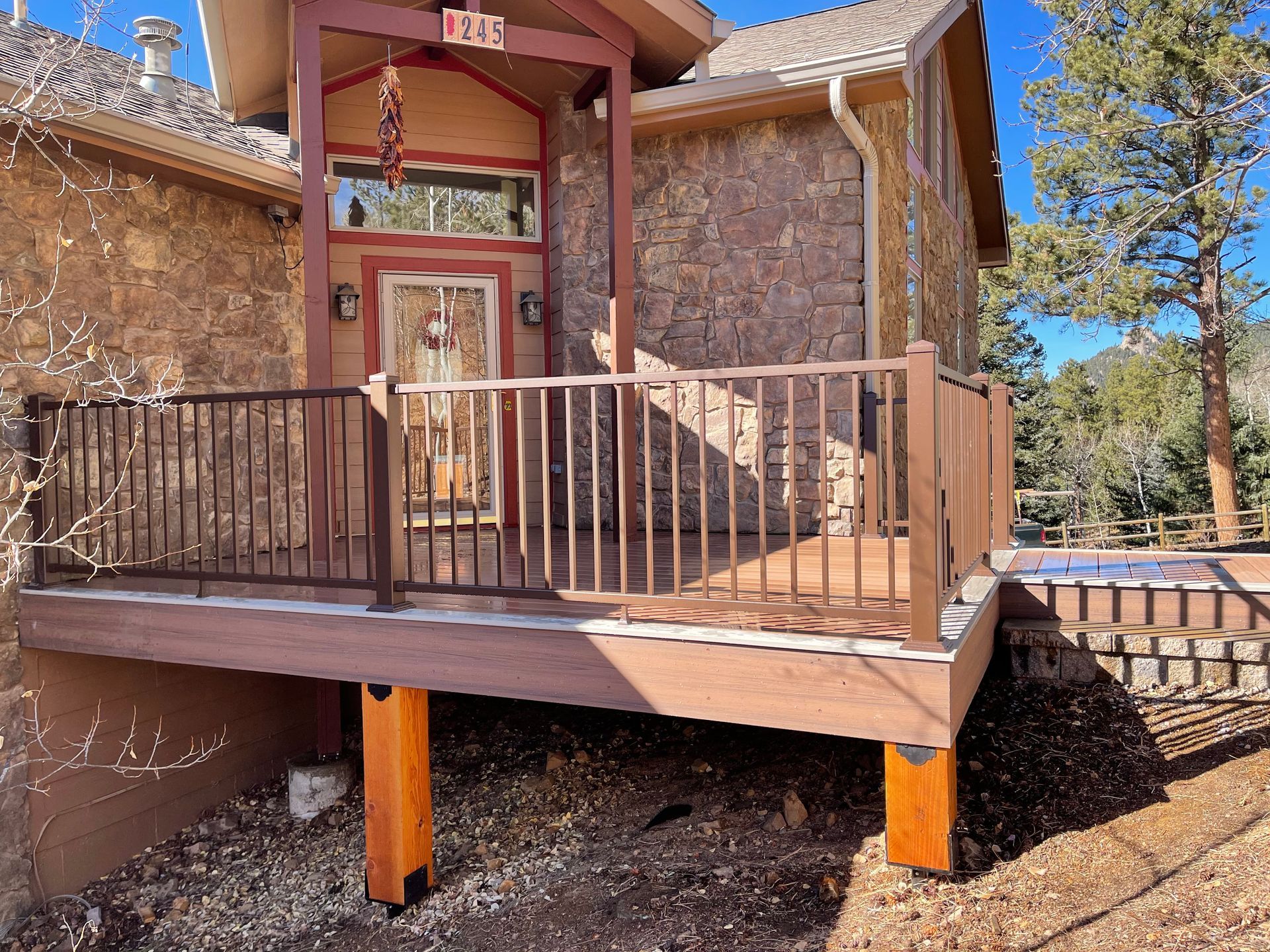 A wooden deck is sitting in front of a stone house.