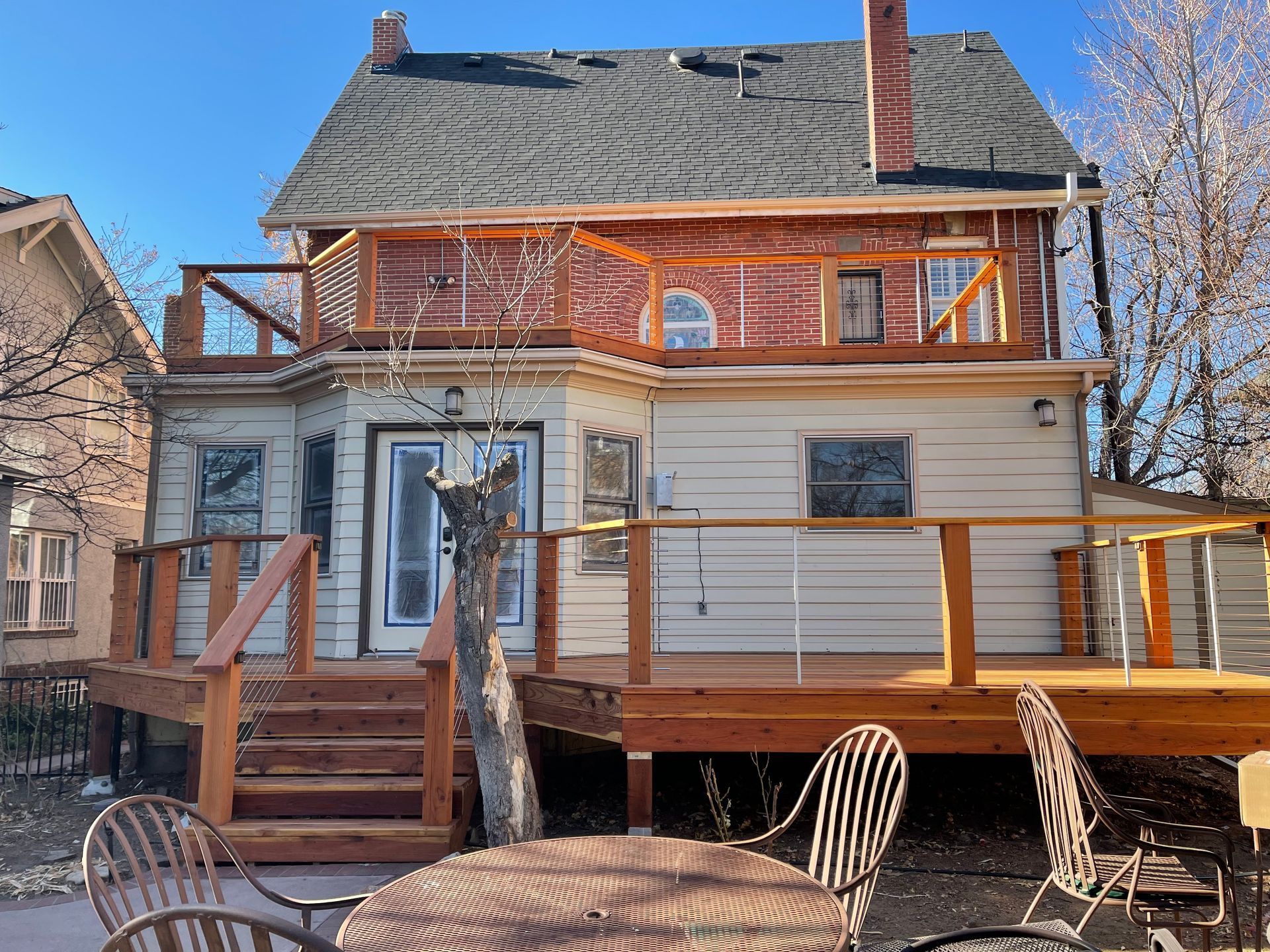 A house with a wooden deck and a table and chairs in front of it