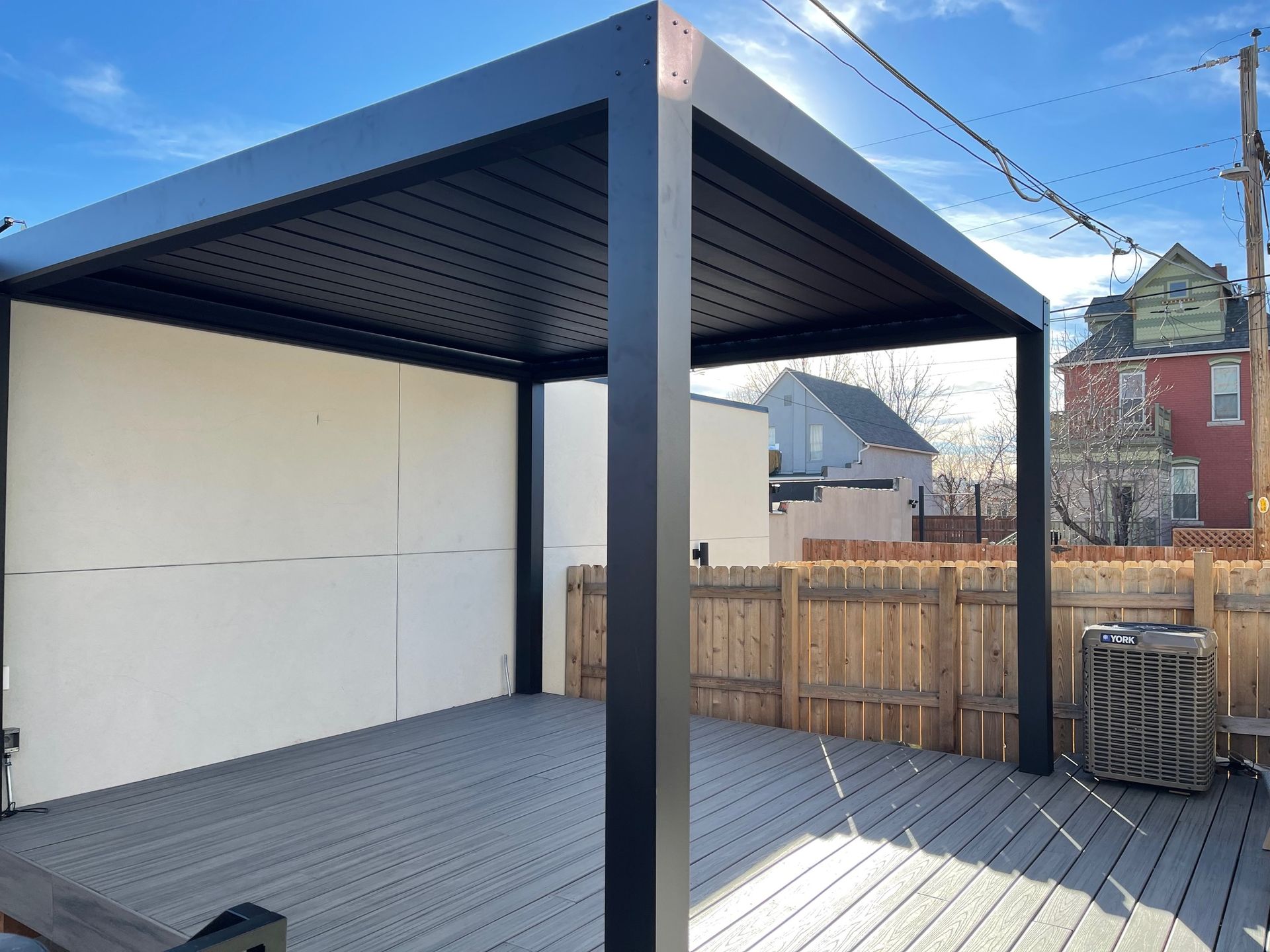 A black pergola is sitting on top of a wooden deck.
