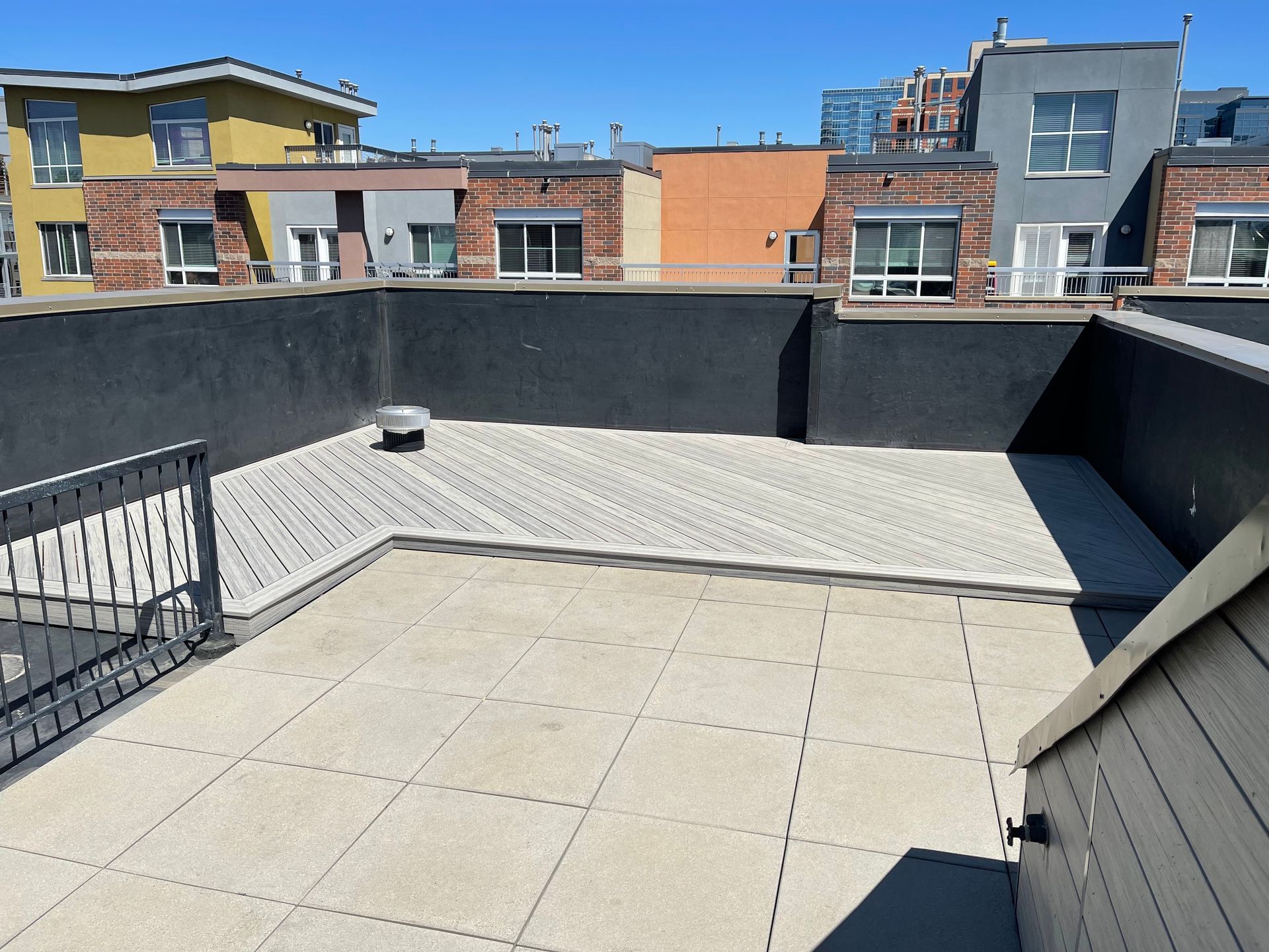 A rooftop with a fence and a few buildings in the background