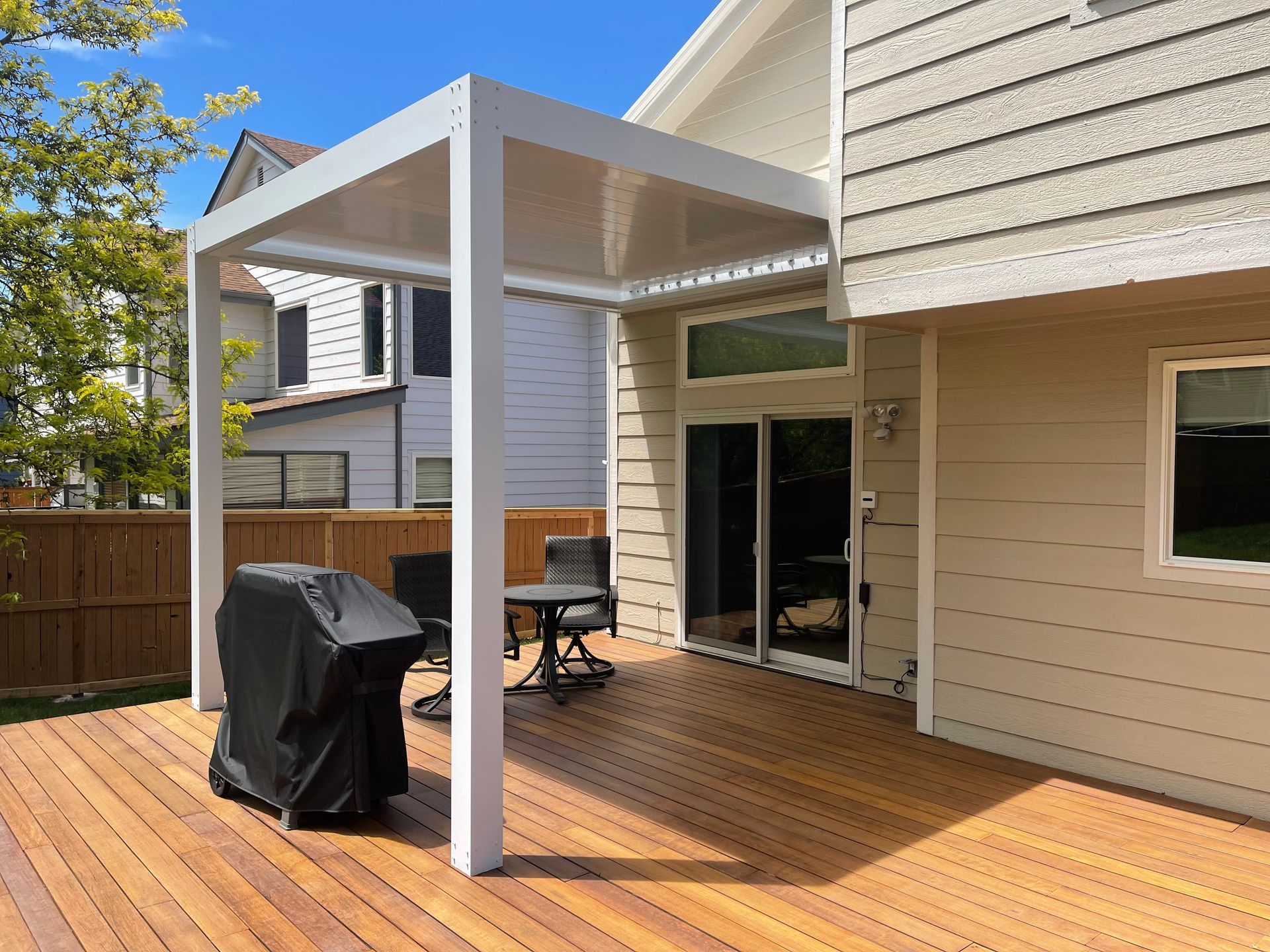 A wooden deck with a table and chairs under a pergola.