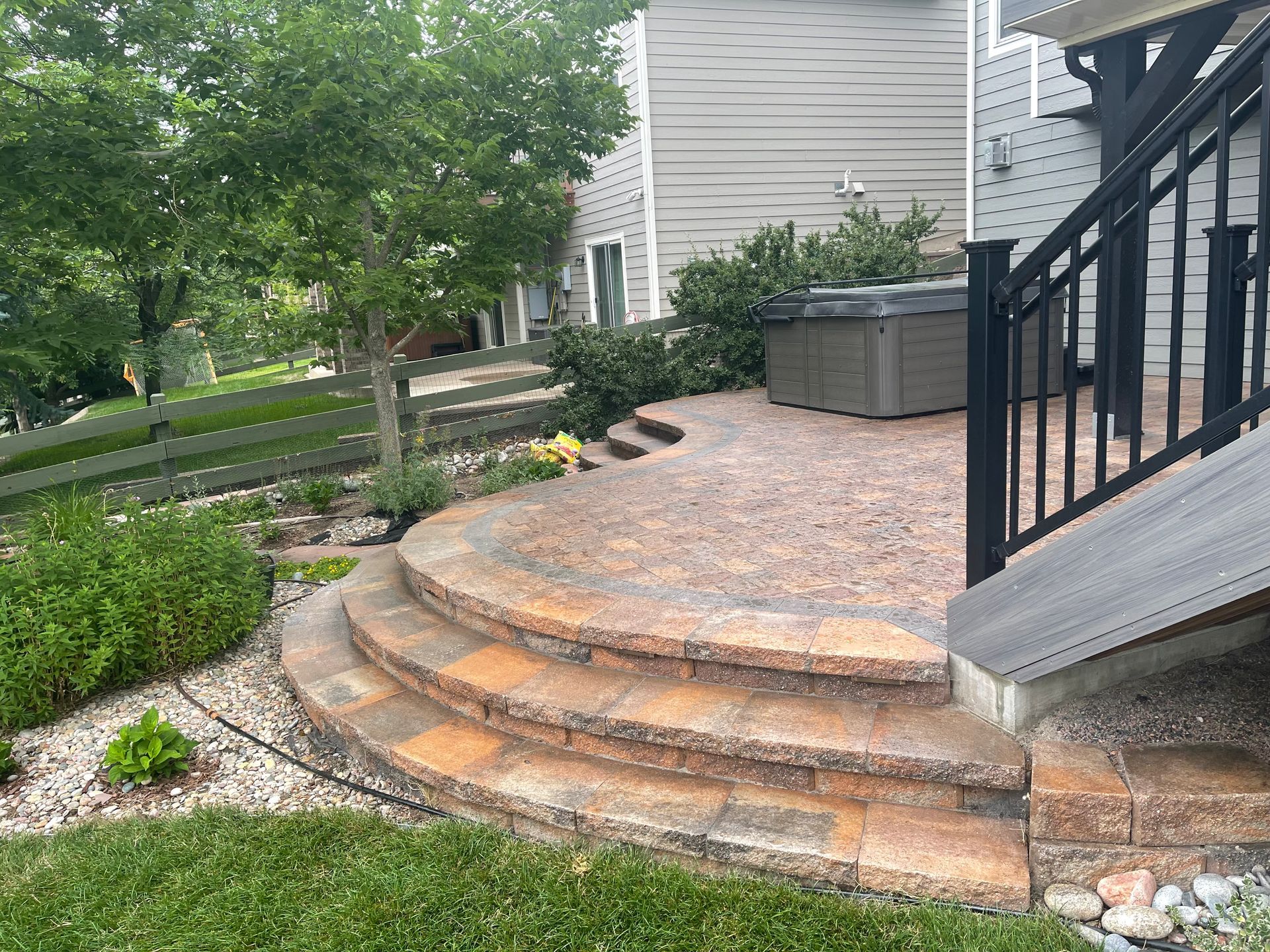 A patio with stairs leading up to it and a hot tub in the background.