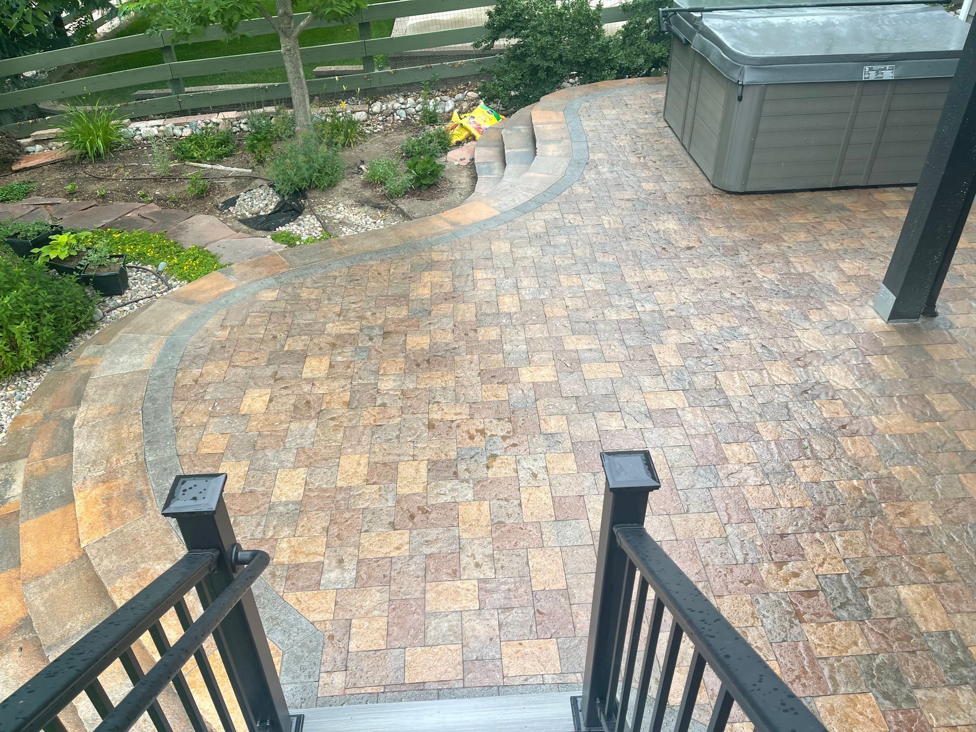 A patio with stairs leading up to it and a hot tub in the background.