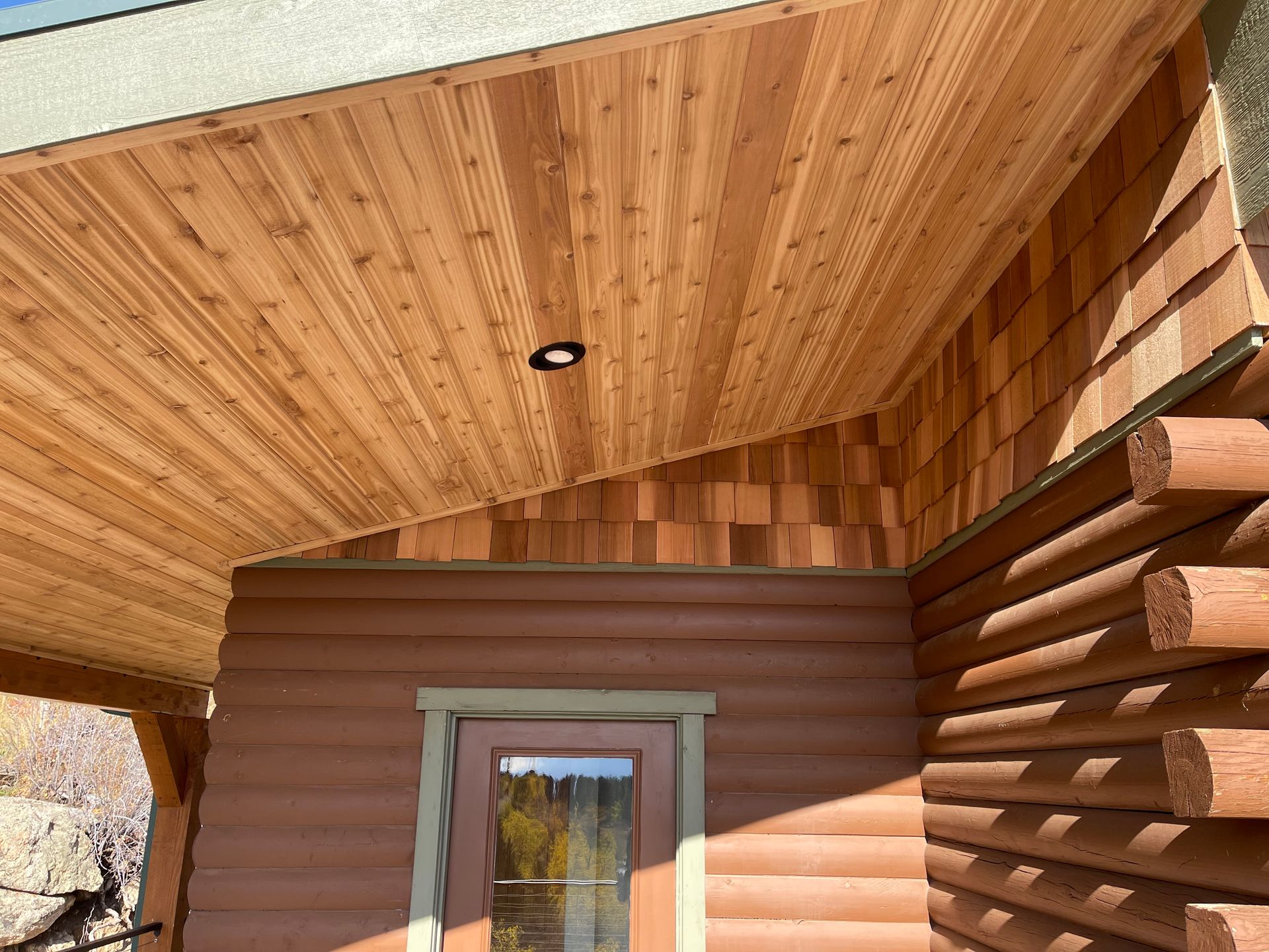 A log cabin with a covered porch and a door.