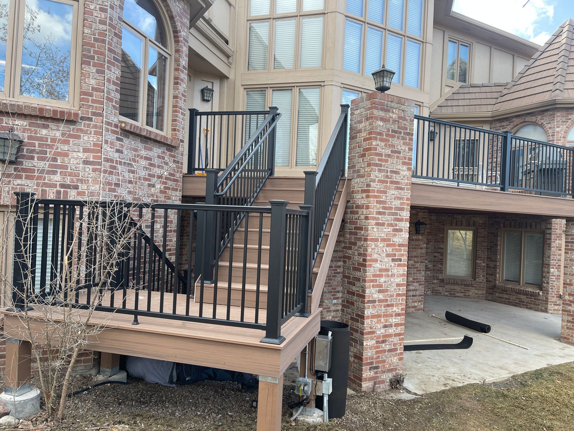 A large brick house with a deck and stairs leading up to it.