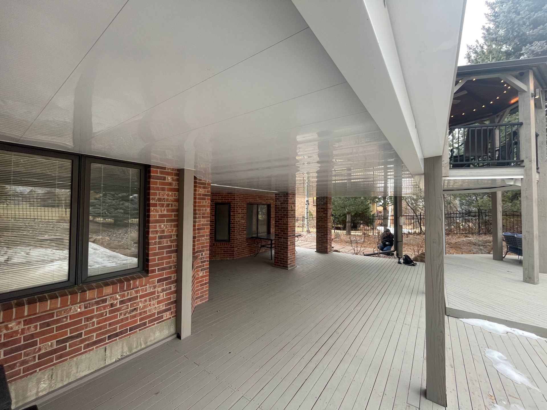 A large covered porch with a brick building in the background