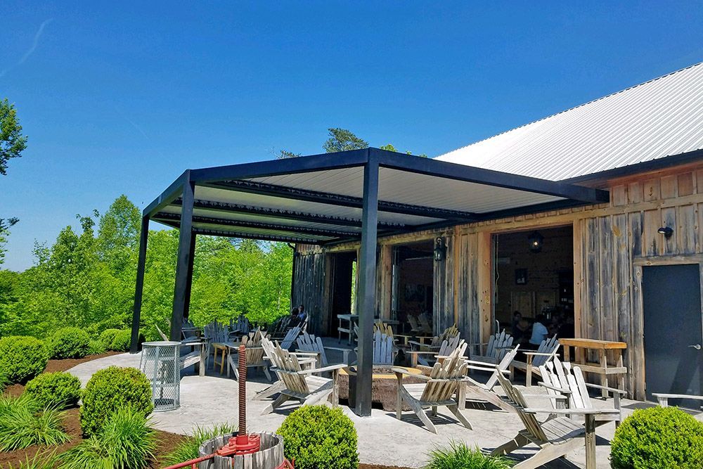 A patio with chairs and tables under a canopy in front of a building.