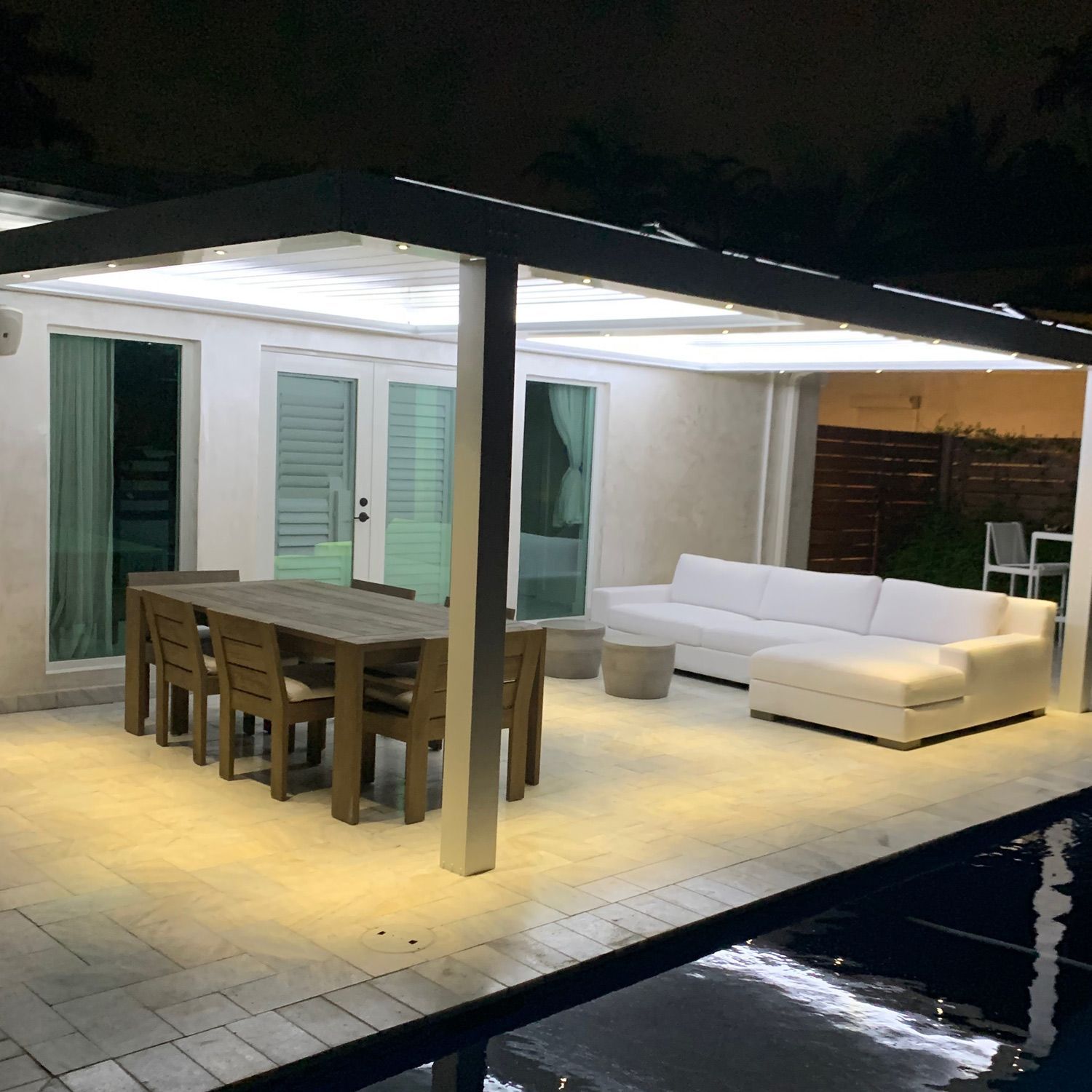 A patio with a couch a table and chairs at night