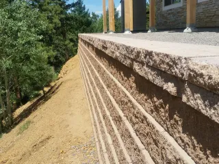 Perfectly straight paver block retaining wall supporting deck column foundation with precision construction and professional finish