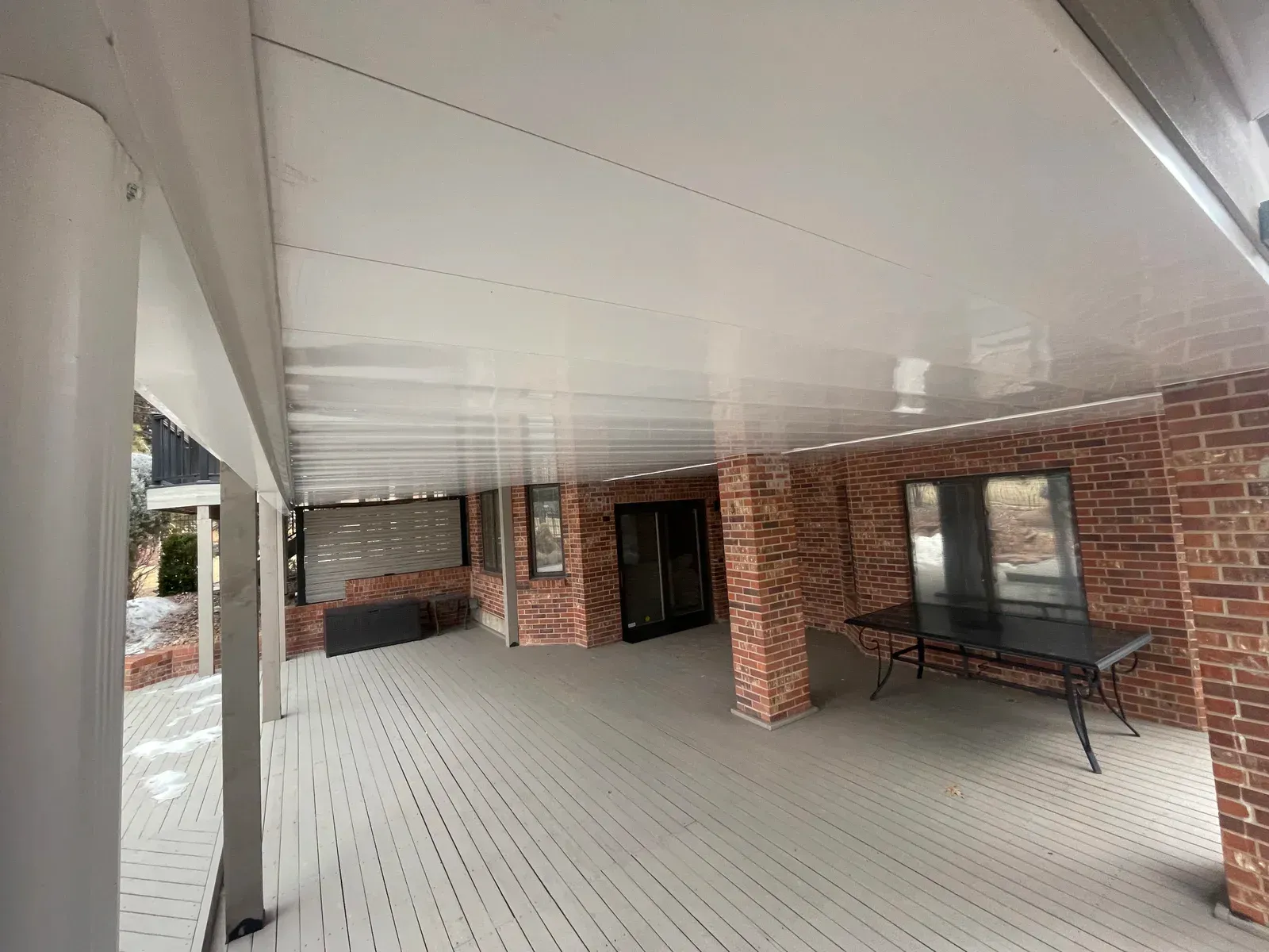 A man is kneeling on a roof with a fence in the background