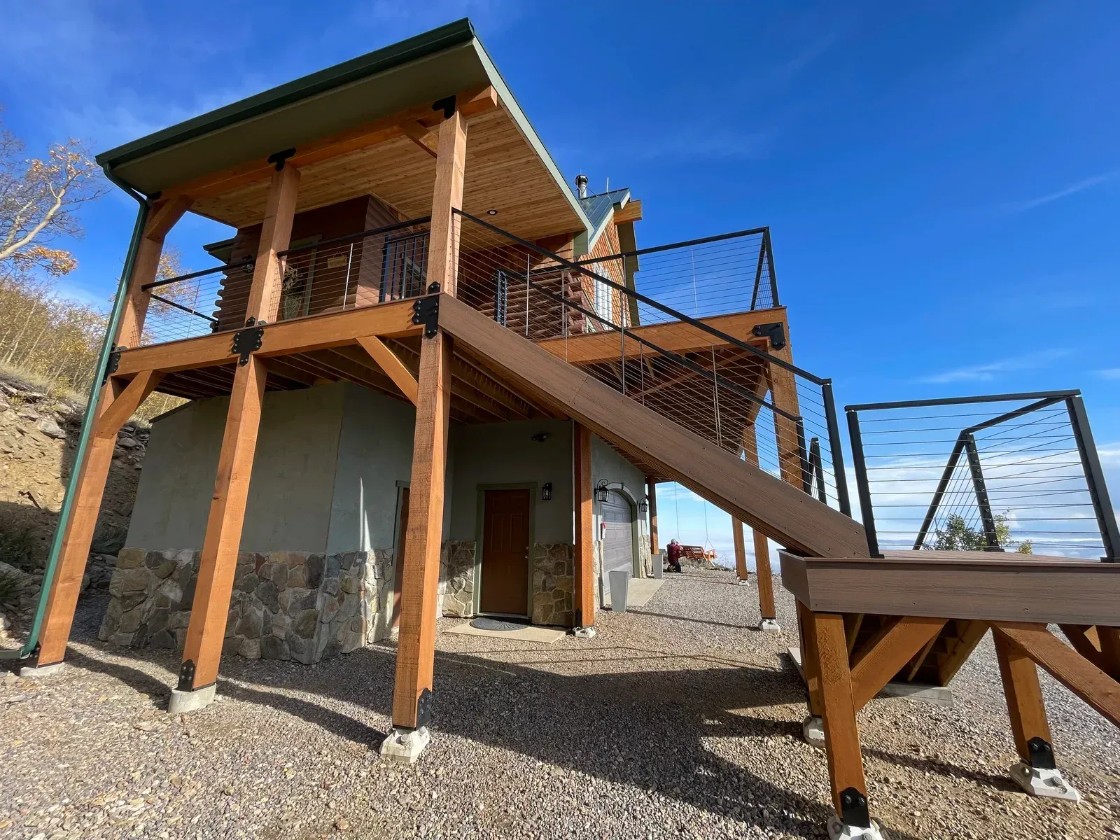 “After photo showing upgraded elevated deck with cable railing, composite stairs, and custom timber supports on a renovated mountain cabin in Colorado.”
