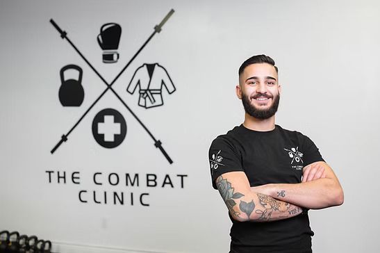 Man with tattoos smiles, stands beside 