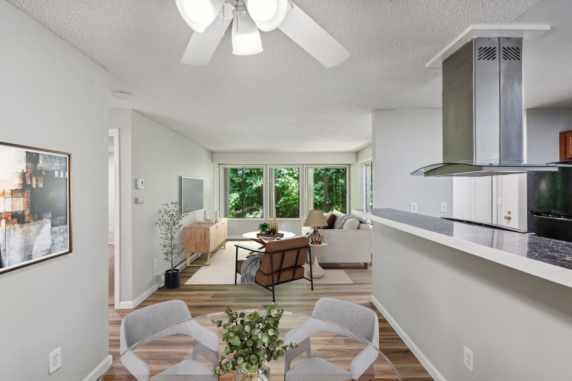 Open-concept apartment living area with dining table, sofa, and kitchen island.