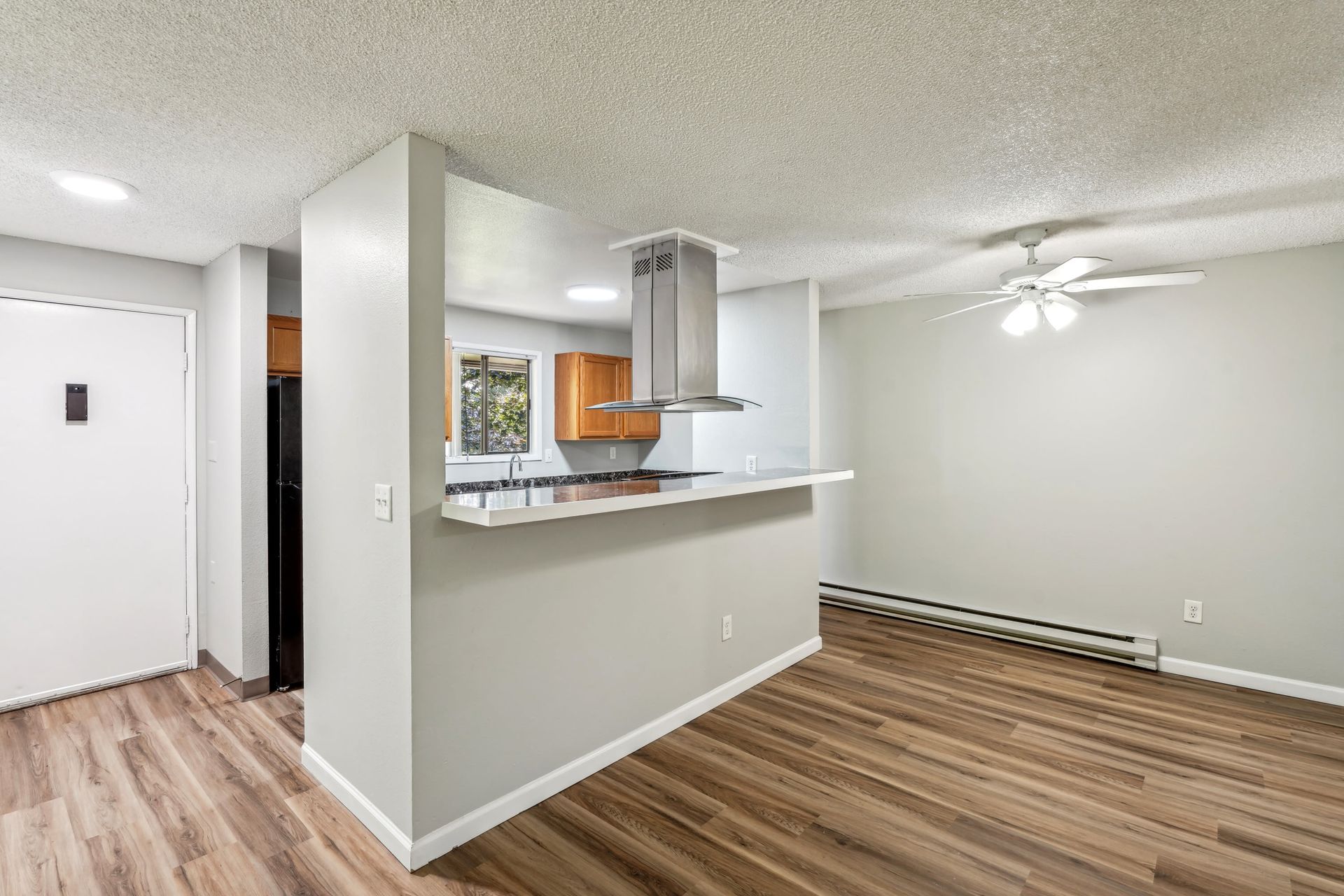 Open-concept kitchen and living area with a breakfast bar and ceiling fan.