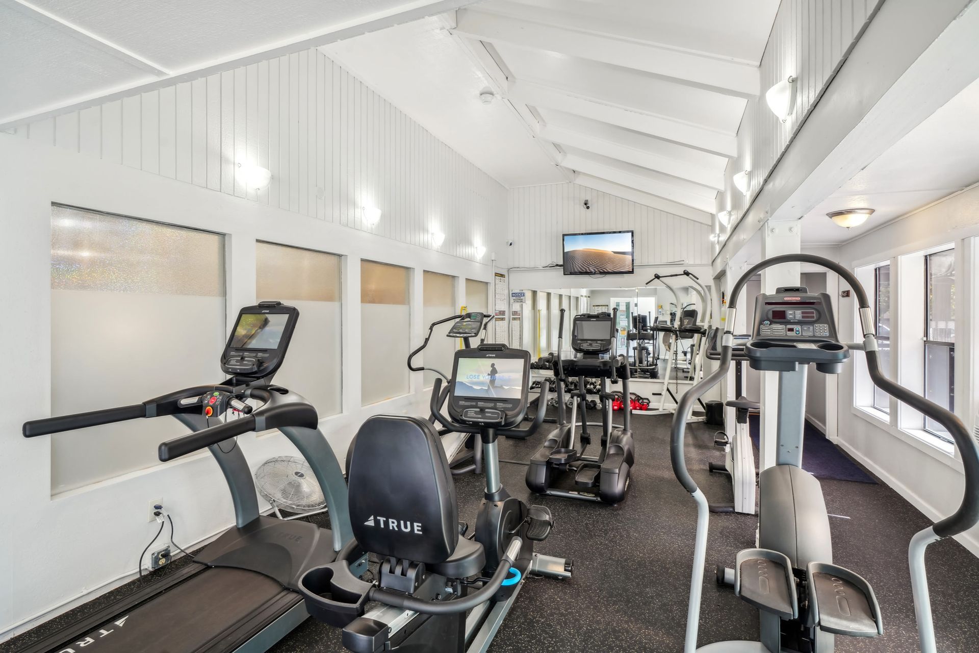 Indoor fitness center with treadmills, ellipticals, and mirrors.
