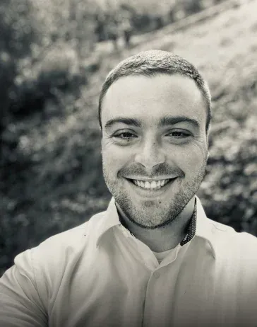 A man with a beard is smiling in a black and white photo.