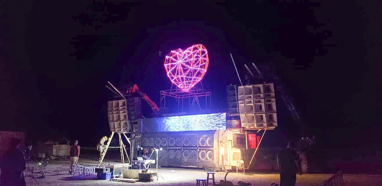 A large heart is lit up at night on a stage.