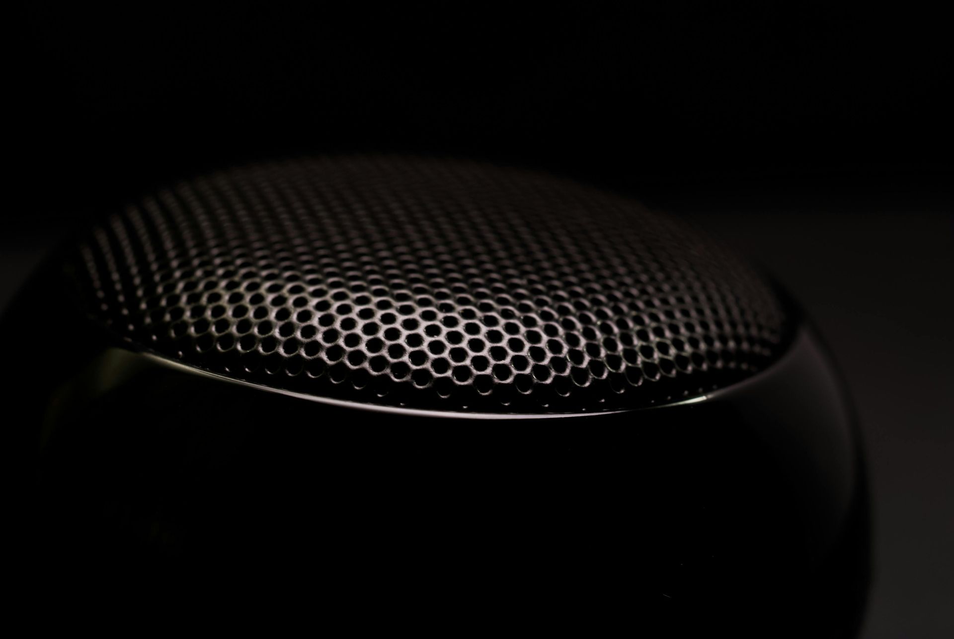 A close up of a black speaker on a black background.
