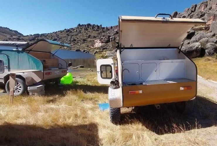 Un camión con un remolque acoplado circula por un camino de tierra.