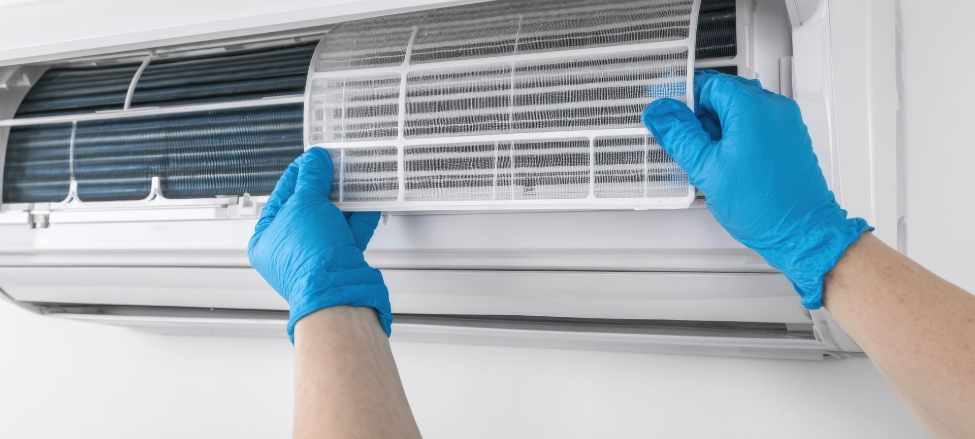 Close up of an air conditioning contractor doing AC services in a blue shirt and gloves.