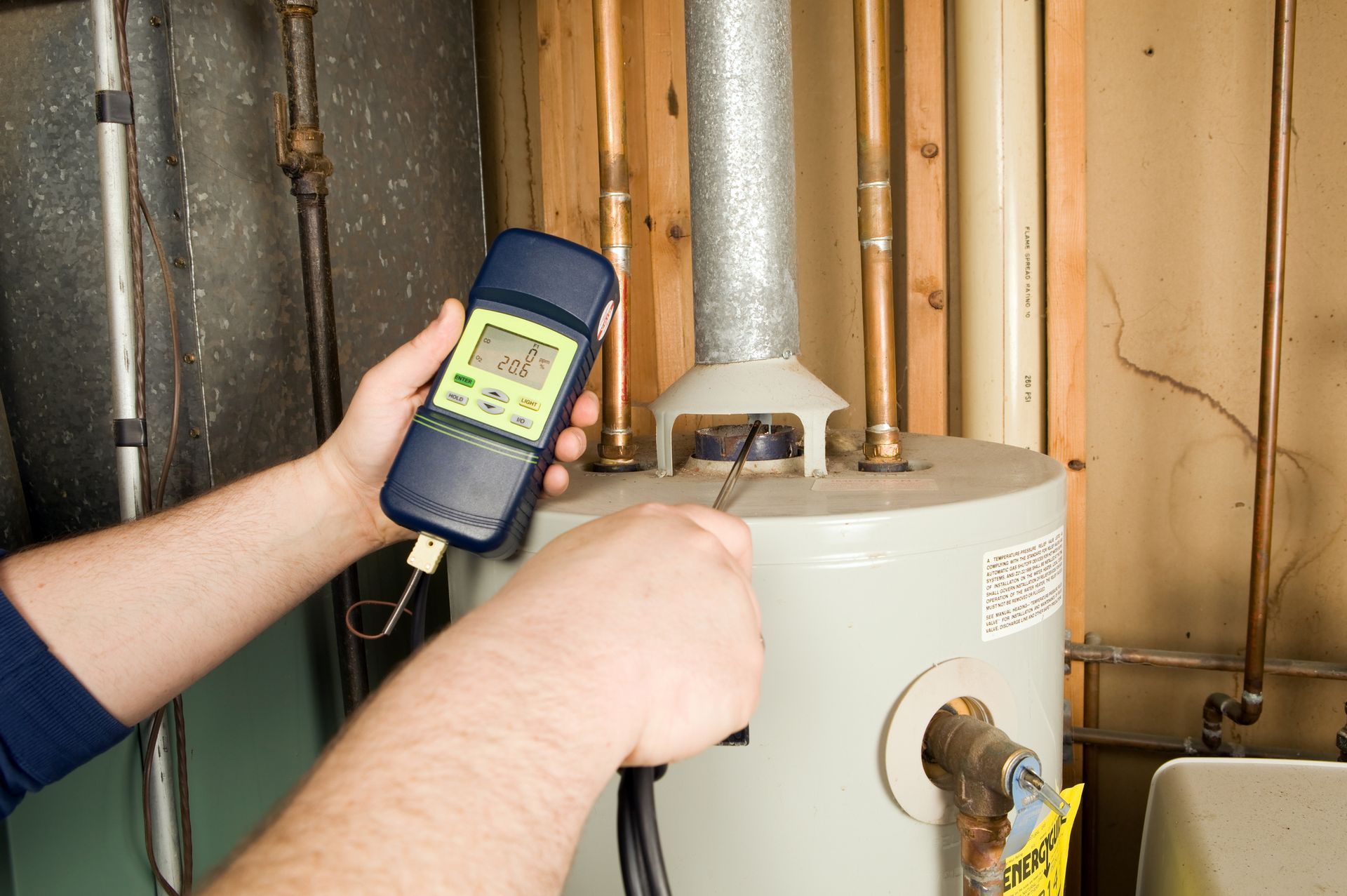 Man checks gas levels of white heater with machine, representing residential heating repairs.