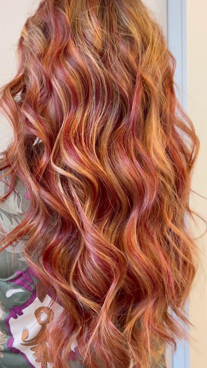 Un primo piano dei capelli di una donna con riflessi rossi e rosa.